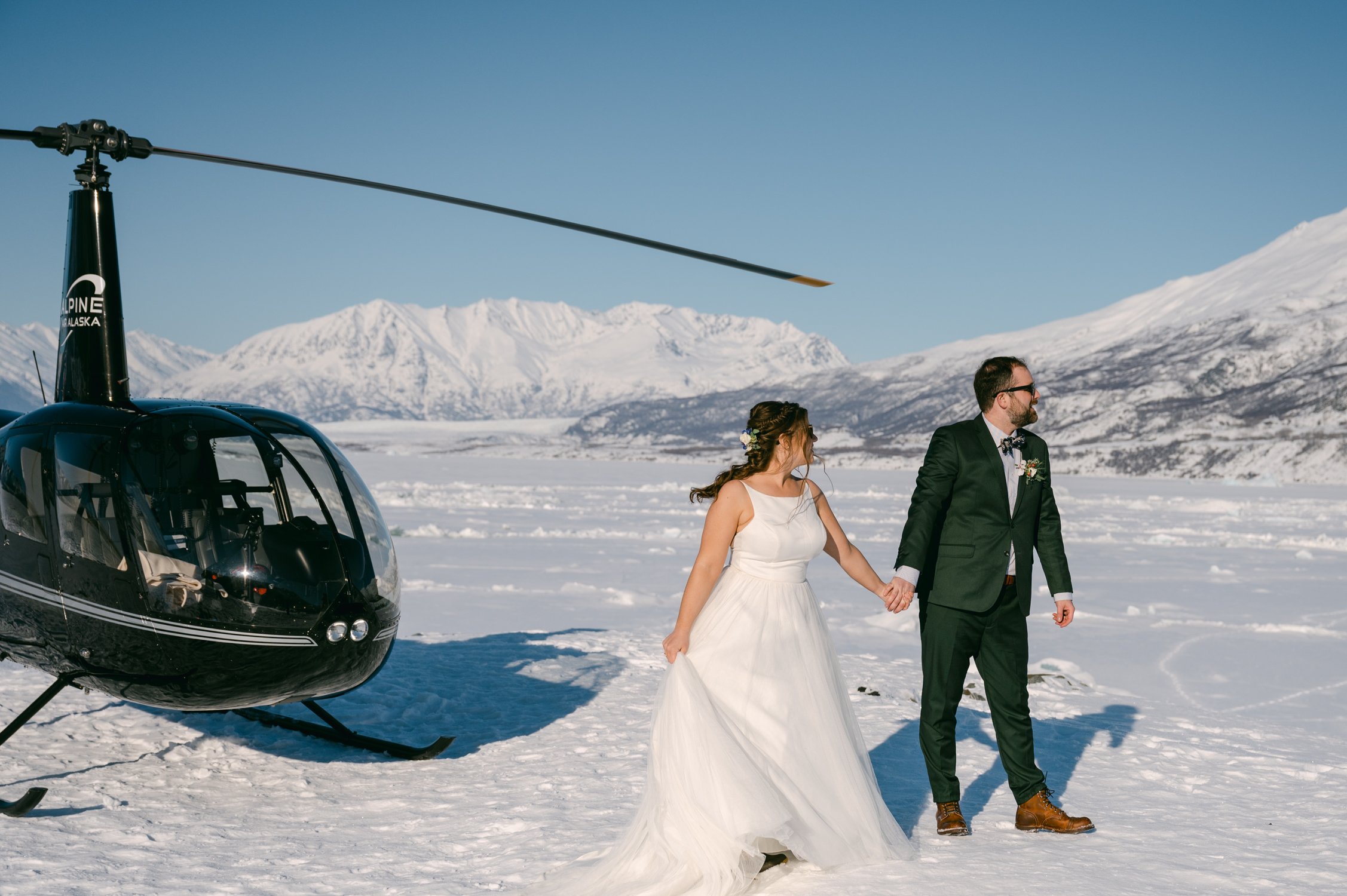 Girdwood Alaska helicopter elopement, photo of a couple walking by a helicopter 