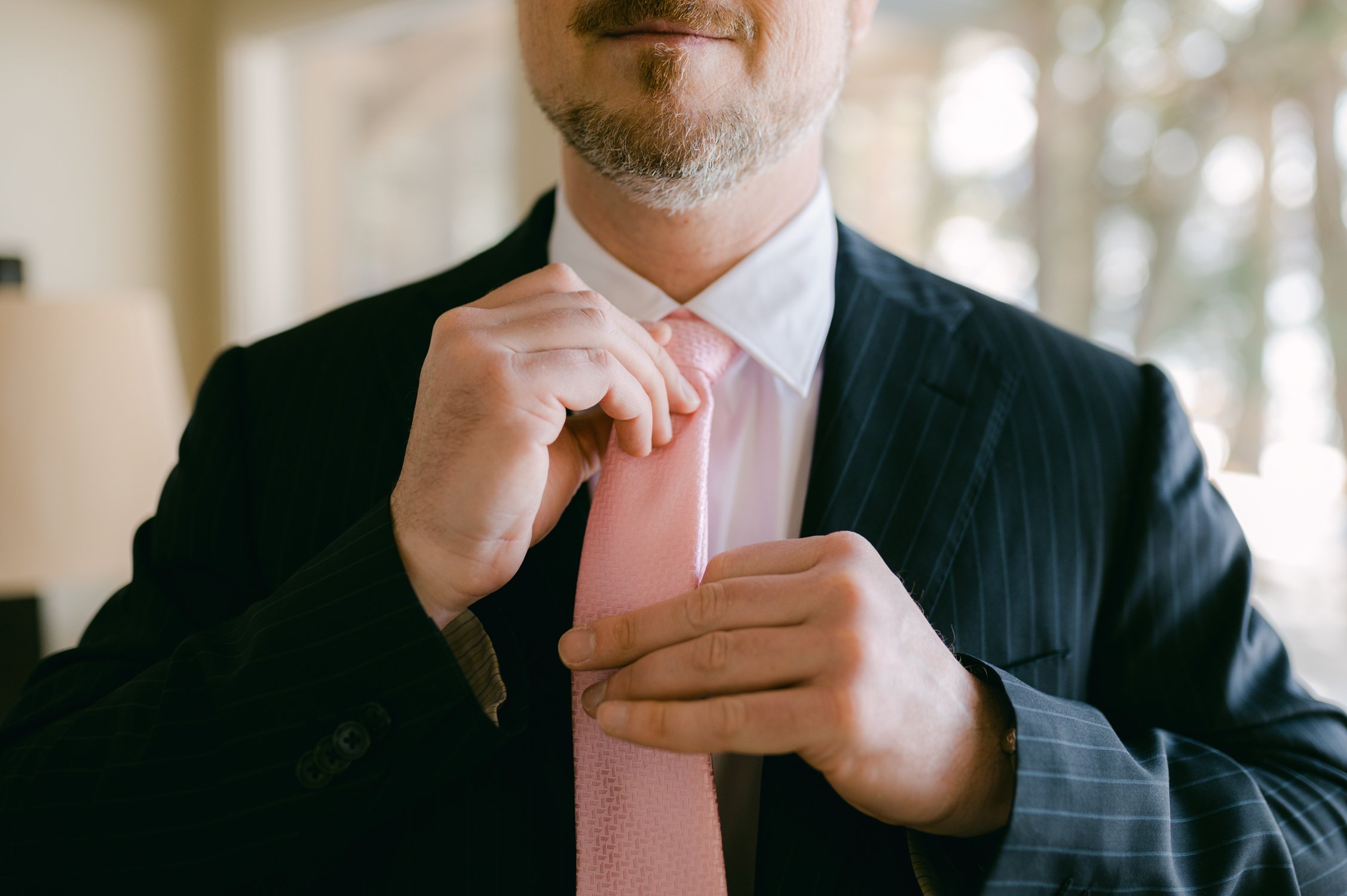 An elopement during a historic winter in tahoe, photo of  groom putting on his tie