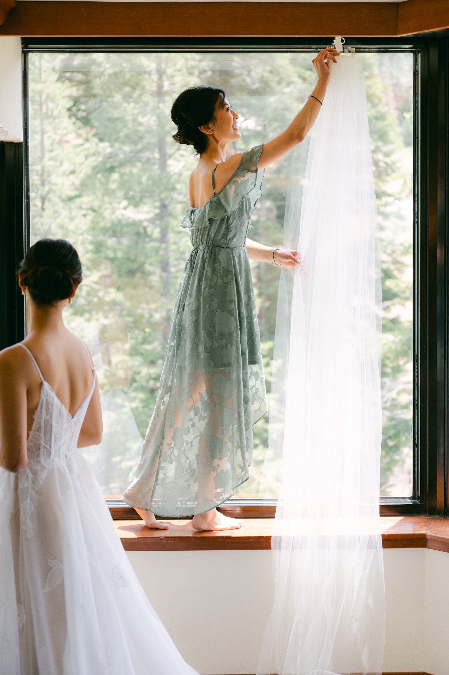 olympic valley stables wedding, photo of the bride and bridesmaid by the window preparing for the wedding