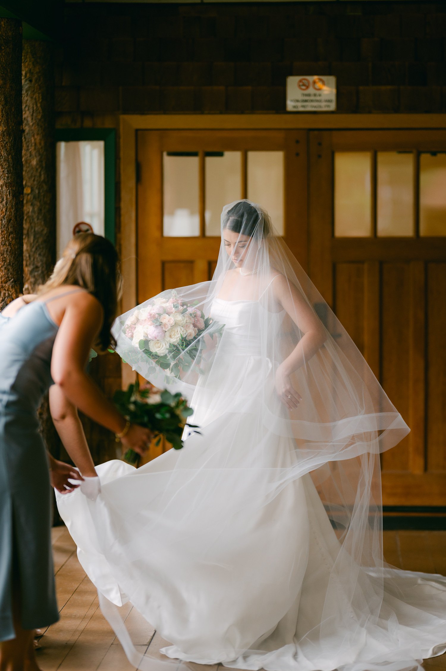 Valhalla Lake Tahoe wedding, photo of the bridesmaid fixing the bride's wedding dress
