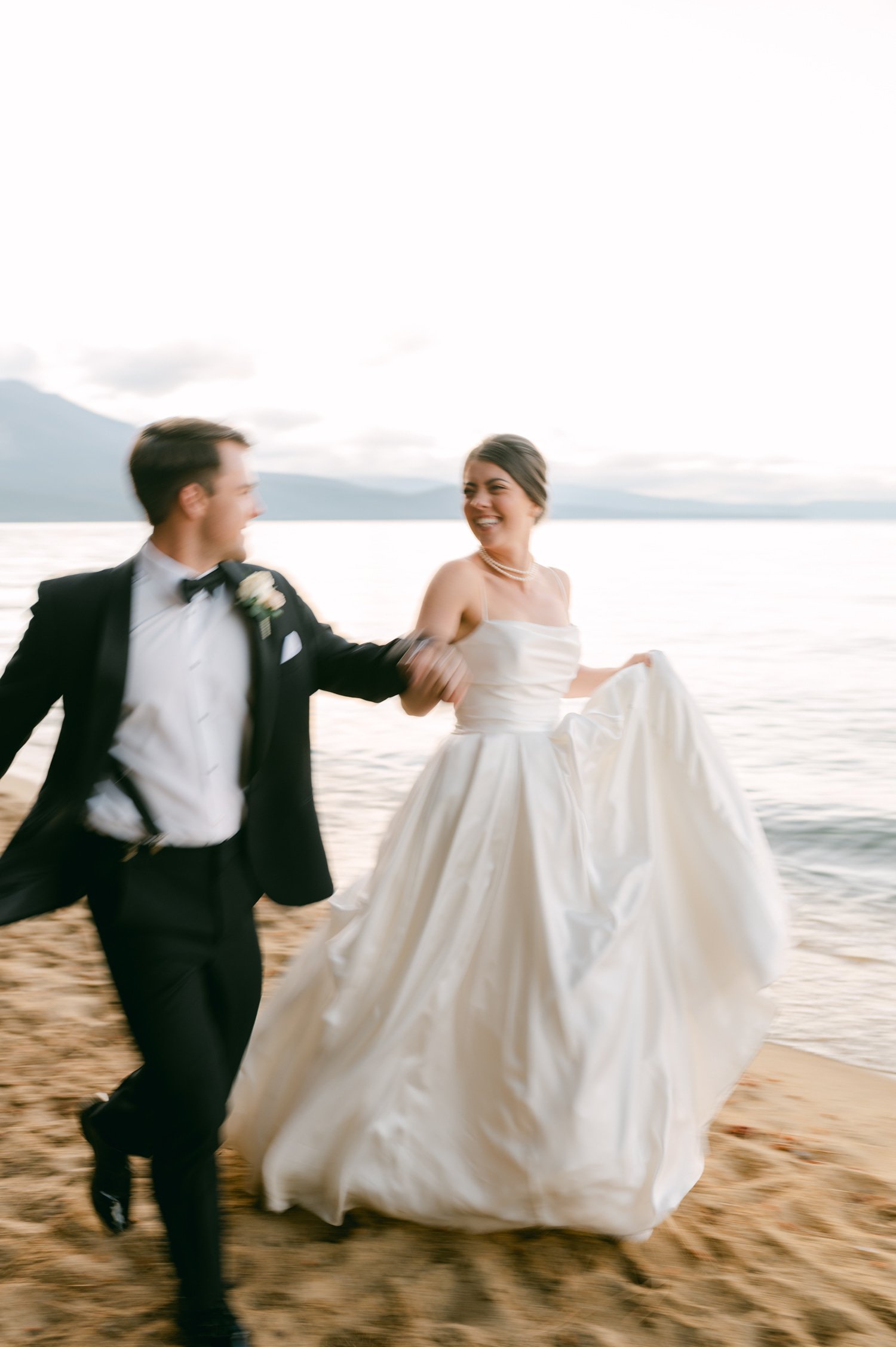 Valhalla Lake Tahoe wedding, photo of the newly wed couple holding hands running by the beach