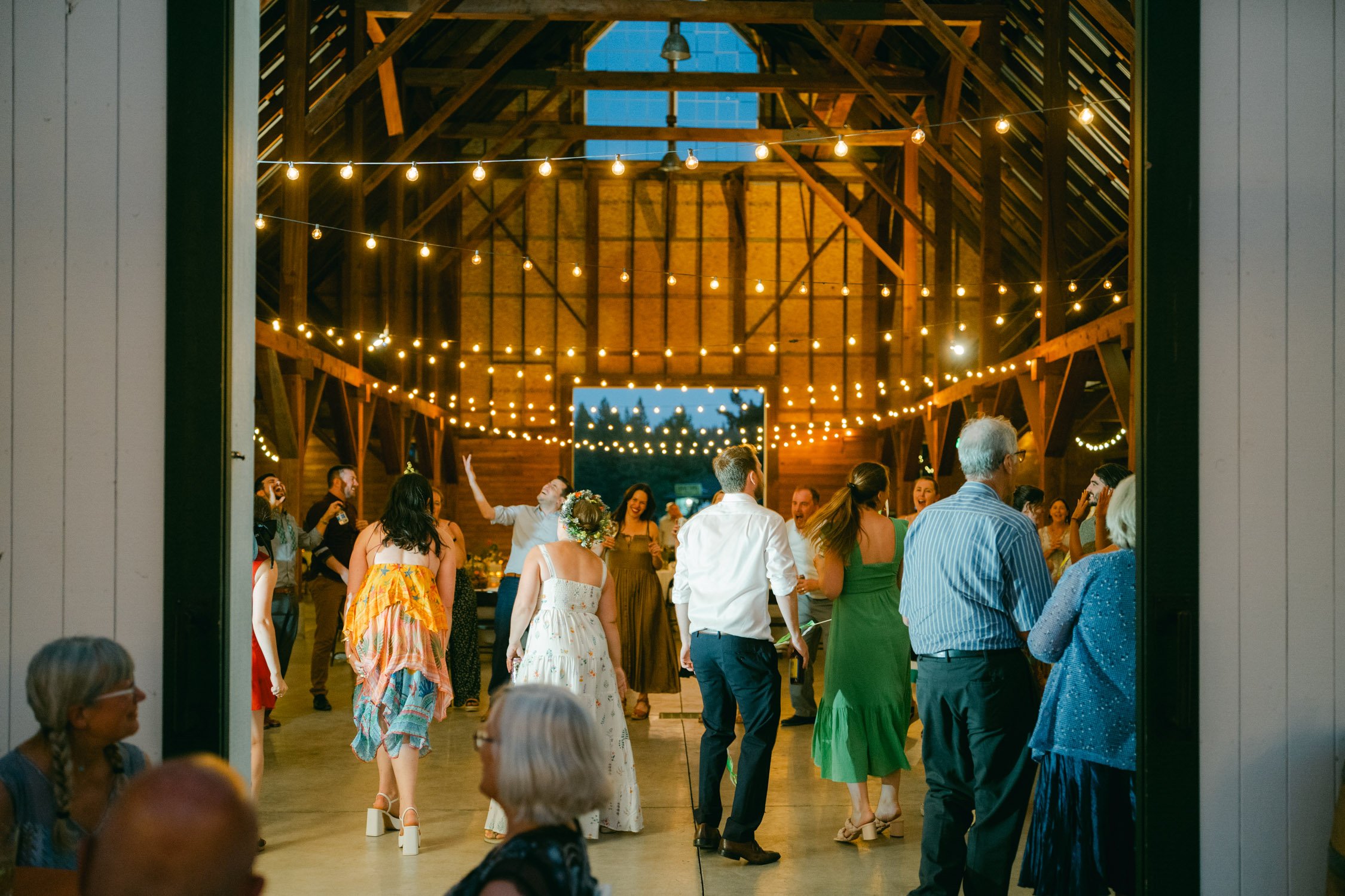 graeagle corner barn wedding, photo of the newly wed couple and guests enjoying during the night reception under the twinkling lights