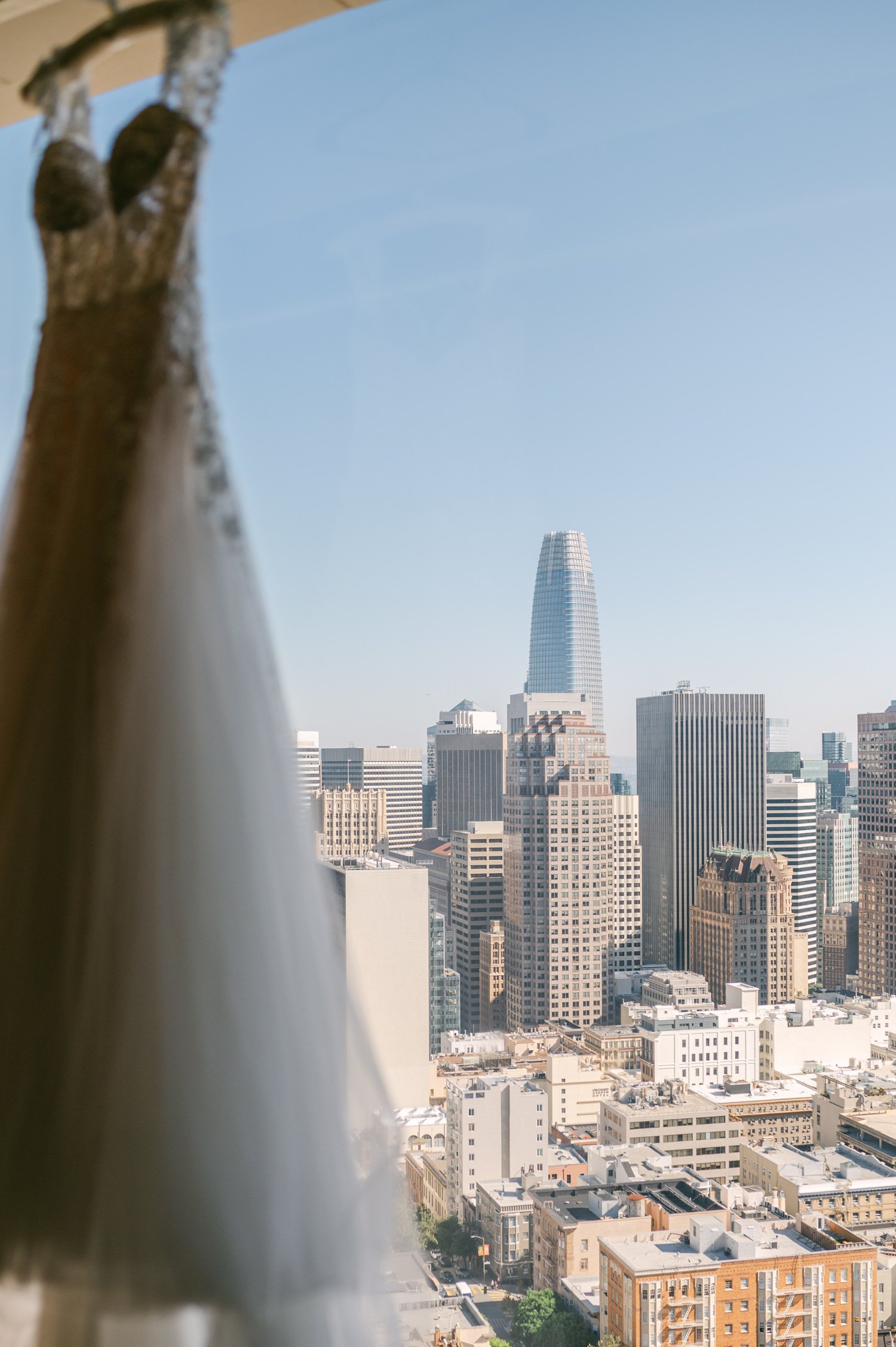 California academy of Sciences in San Francisco Wedding, photo of the wedding dress hanging by the window with the view of the city