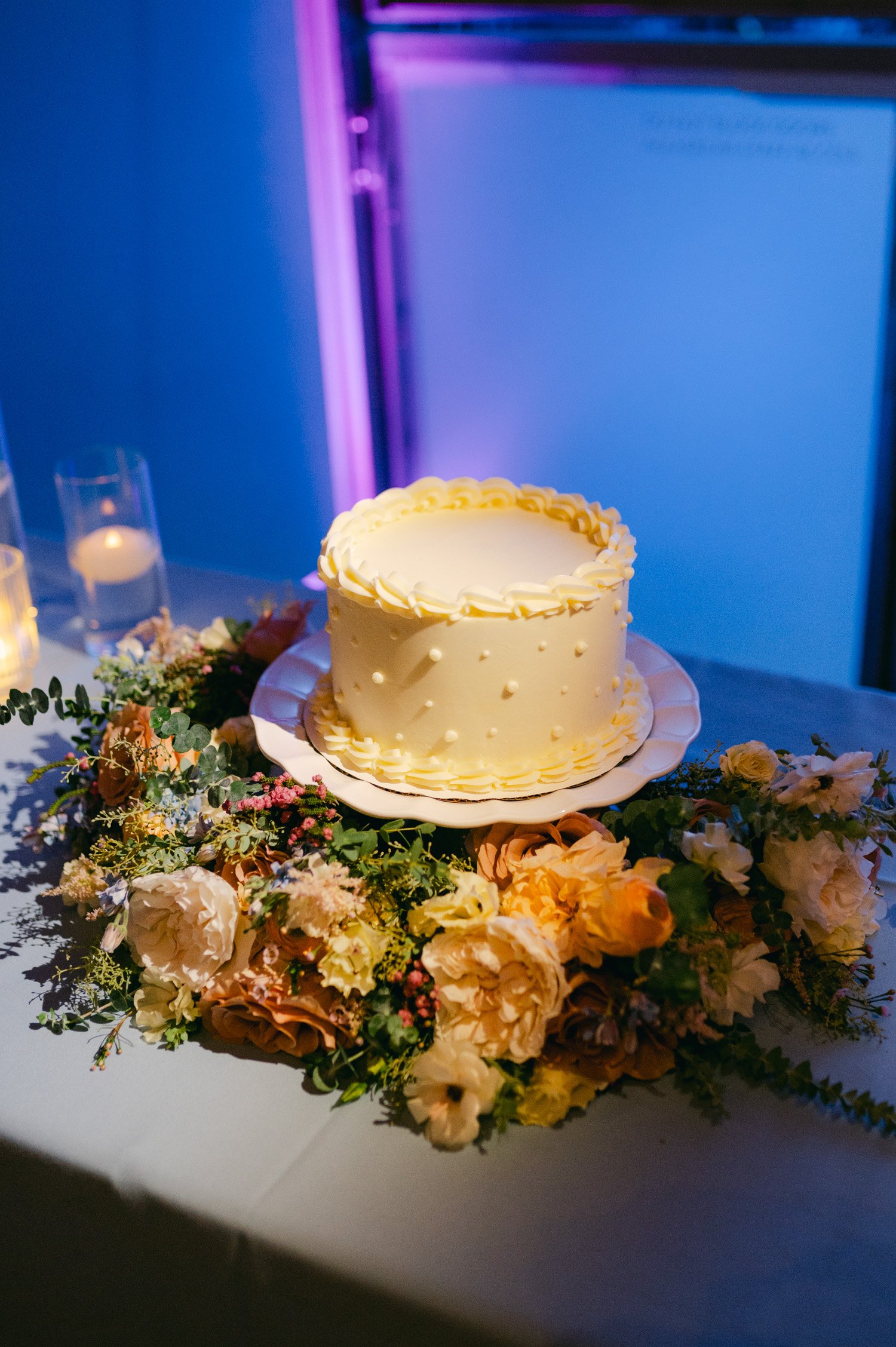 California academy of Sciences in San Francisco Wedding, photo of a minimal 1 layer wedding cake with pearl accents and flowers surrounding the table