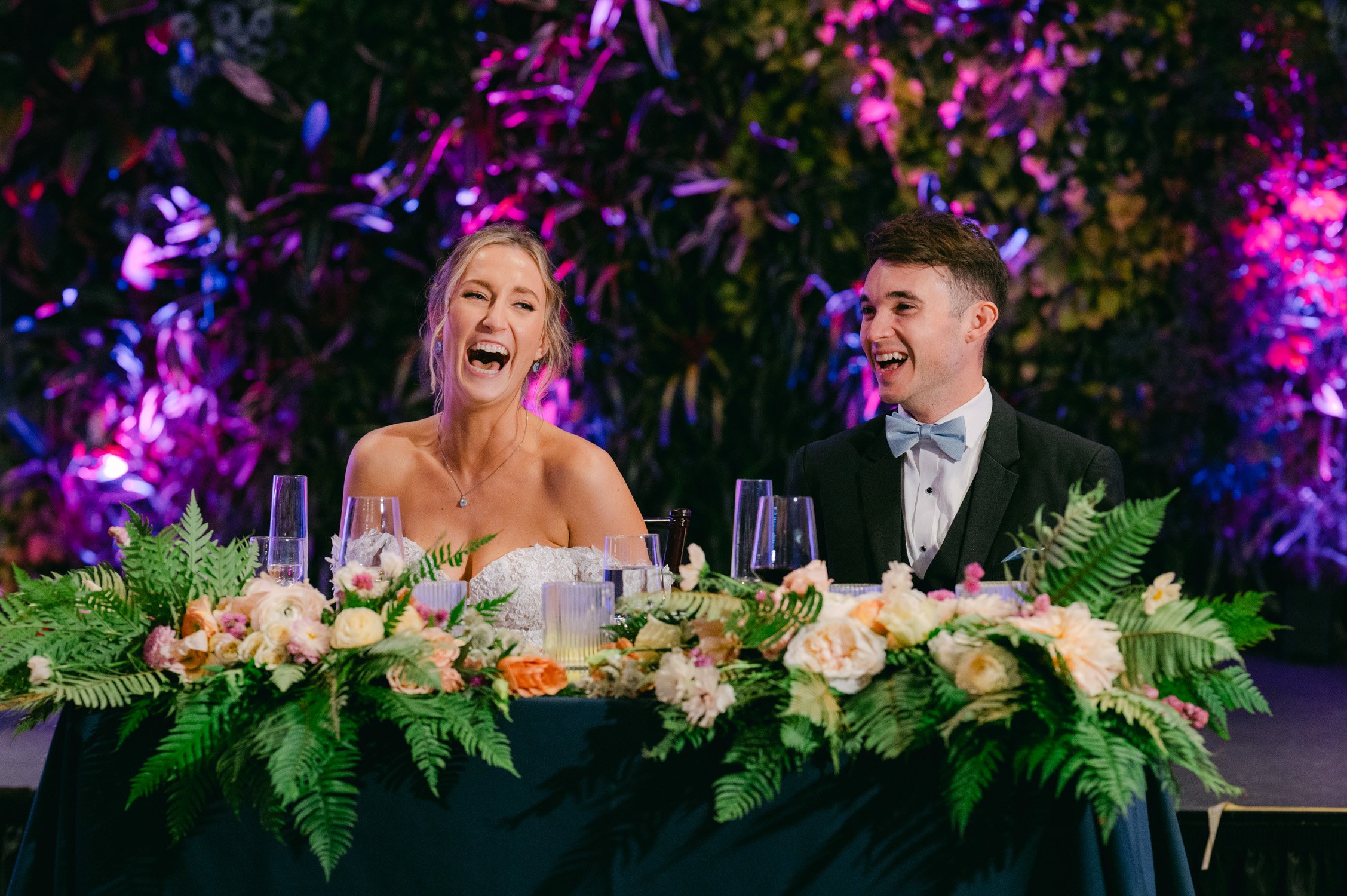 California academy of Sciences in San Francisco Wedding, photo of the newly wed couple sitting on their table laughing while listening to the speeches