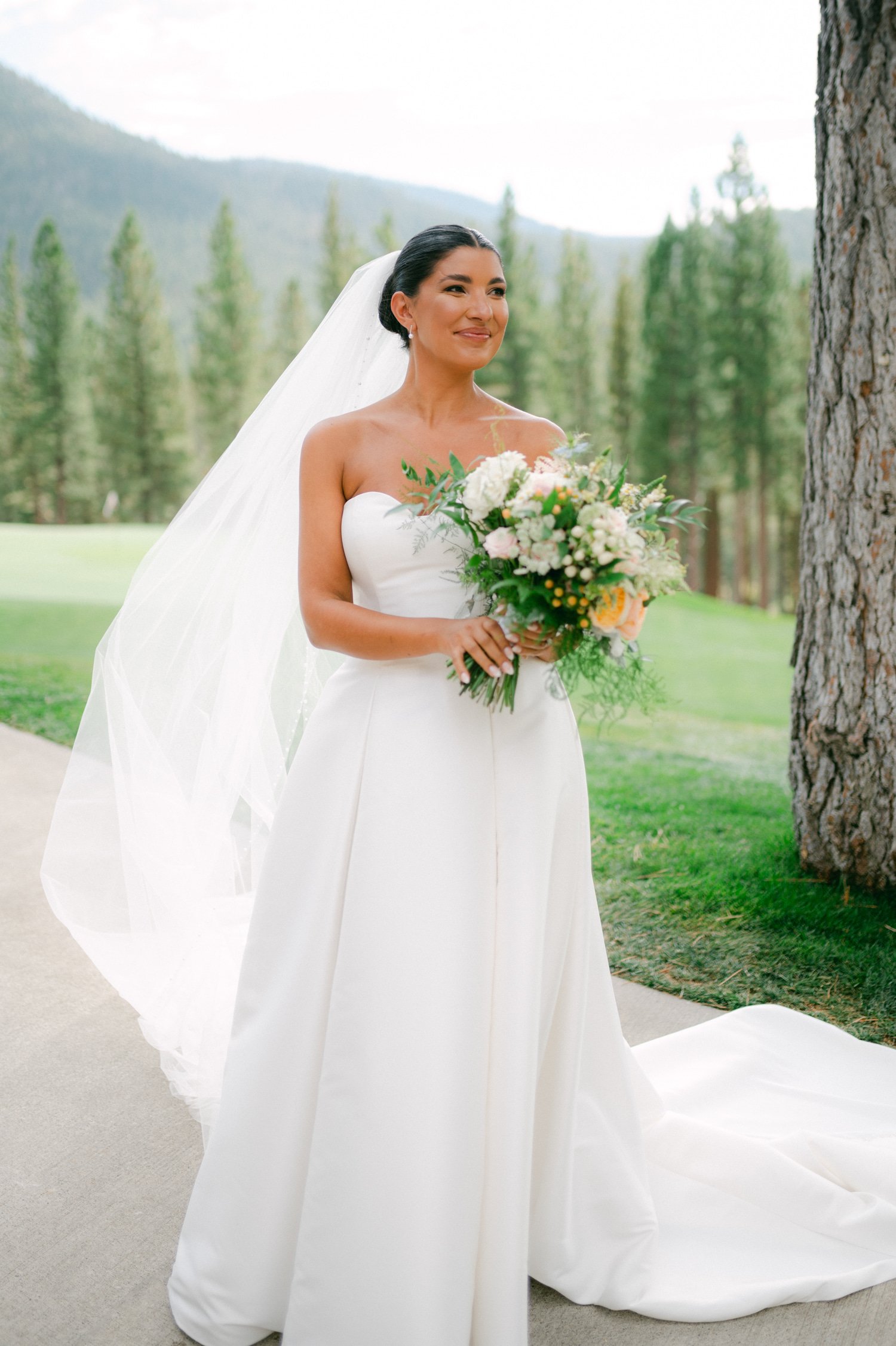 Martis Camp Wedding, photo portrait of the bride in her simple wedding dress with long veil holding her wedding bouquet