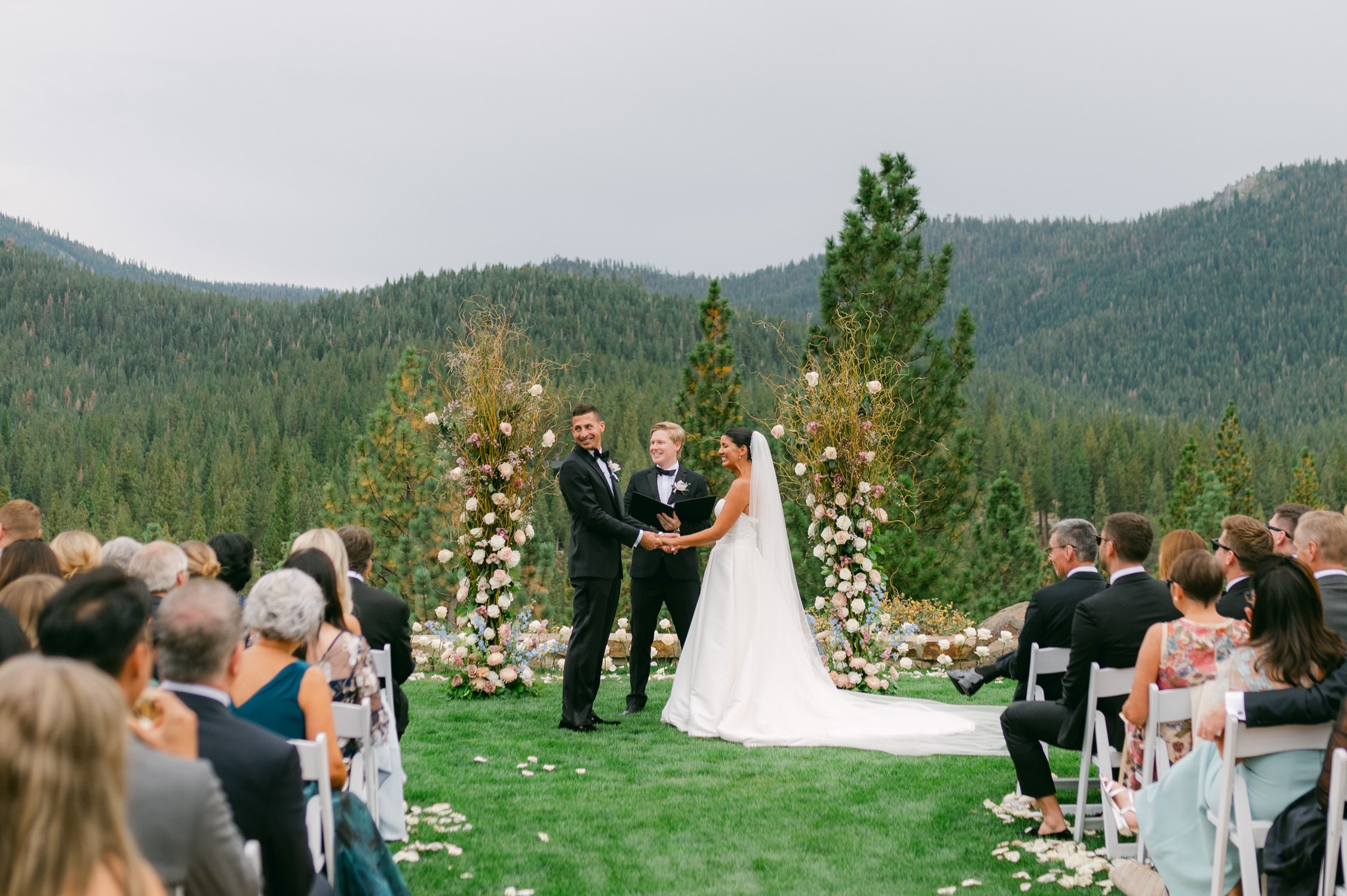 Martis Camp Wedding, photo of the wedding couple holding hands during their outdoor ceremony looking at their guests