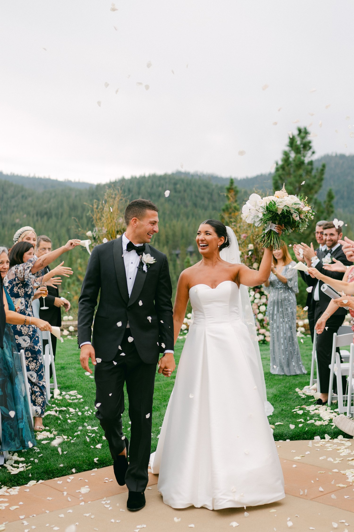 Martis Camp Wedding, photo of the newlywed couple walking down the aisle while guests are tossing white petals 