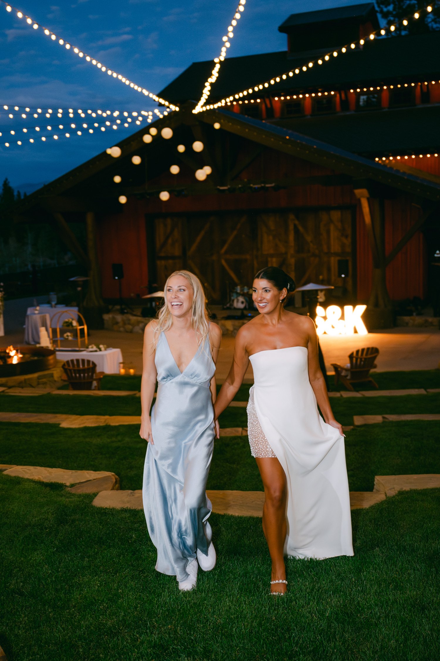 Martis Camp Wedding, photo of the bride in her second dress and guest in blue dress walking to the evening reception
