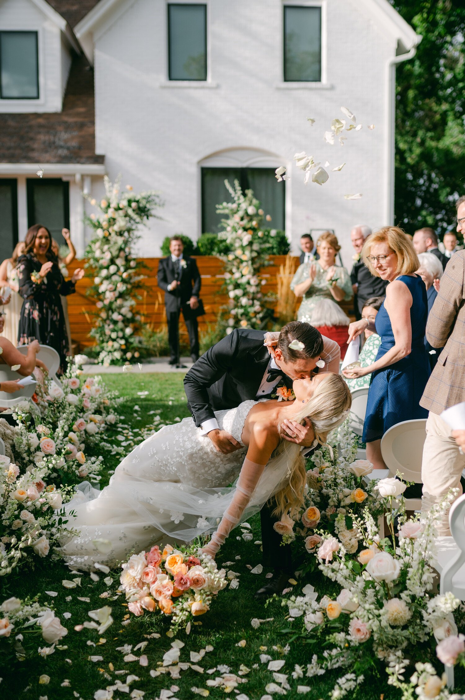 Elm Estate Wedding photo, photo of the bride and groom kissing and dipping with flower petals being thrown at them during their ceremony exit