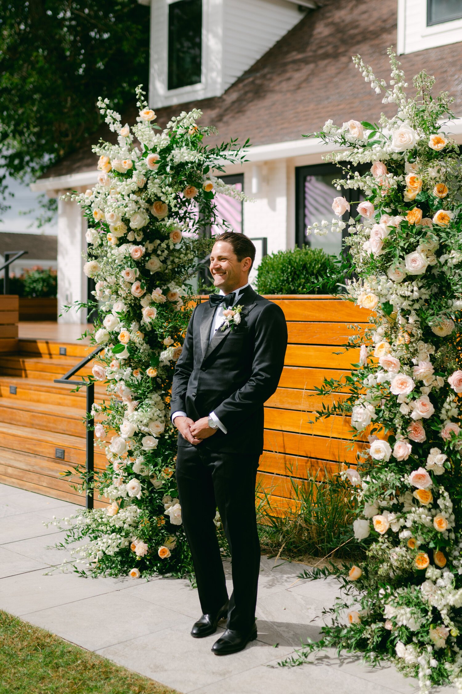 Elm Estate Wedding photos, photo of the groom standing in between paste colored flower towers while waiting for the bride