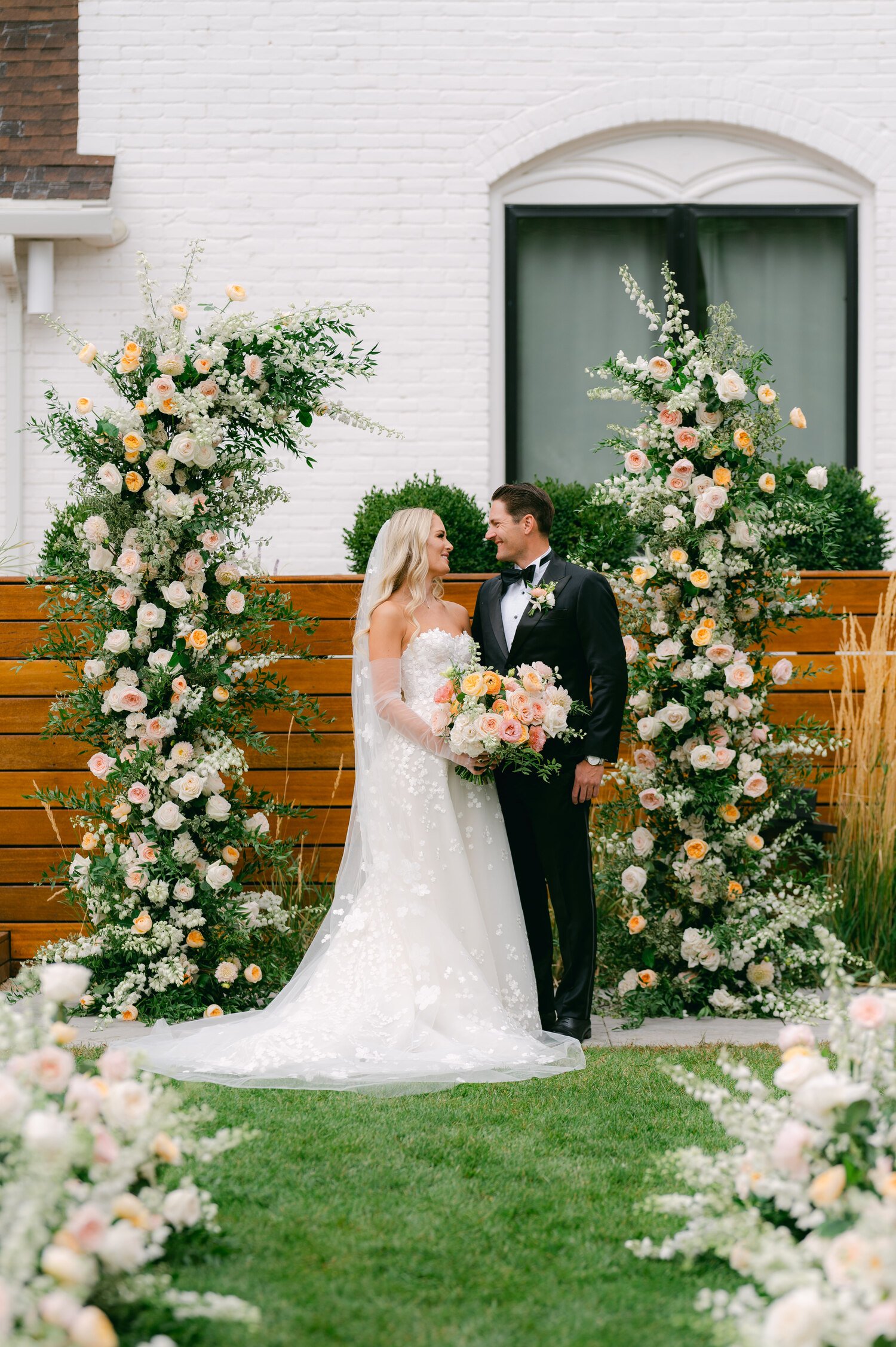 Elm Estate Wedding photos, photo of the bride in her elegant wedding dress and the groom in classic wedding suit surrounded by blooming flowers 