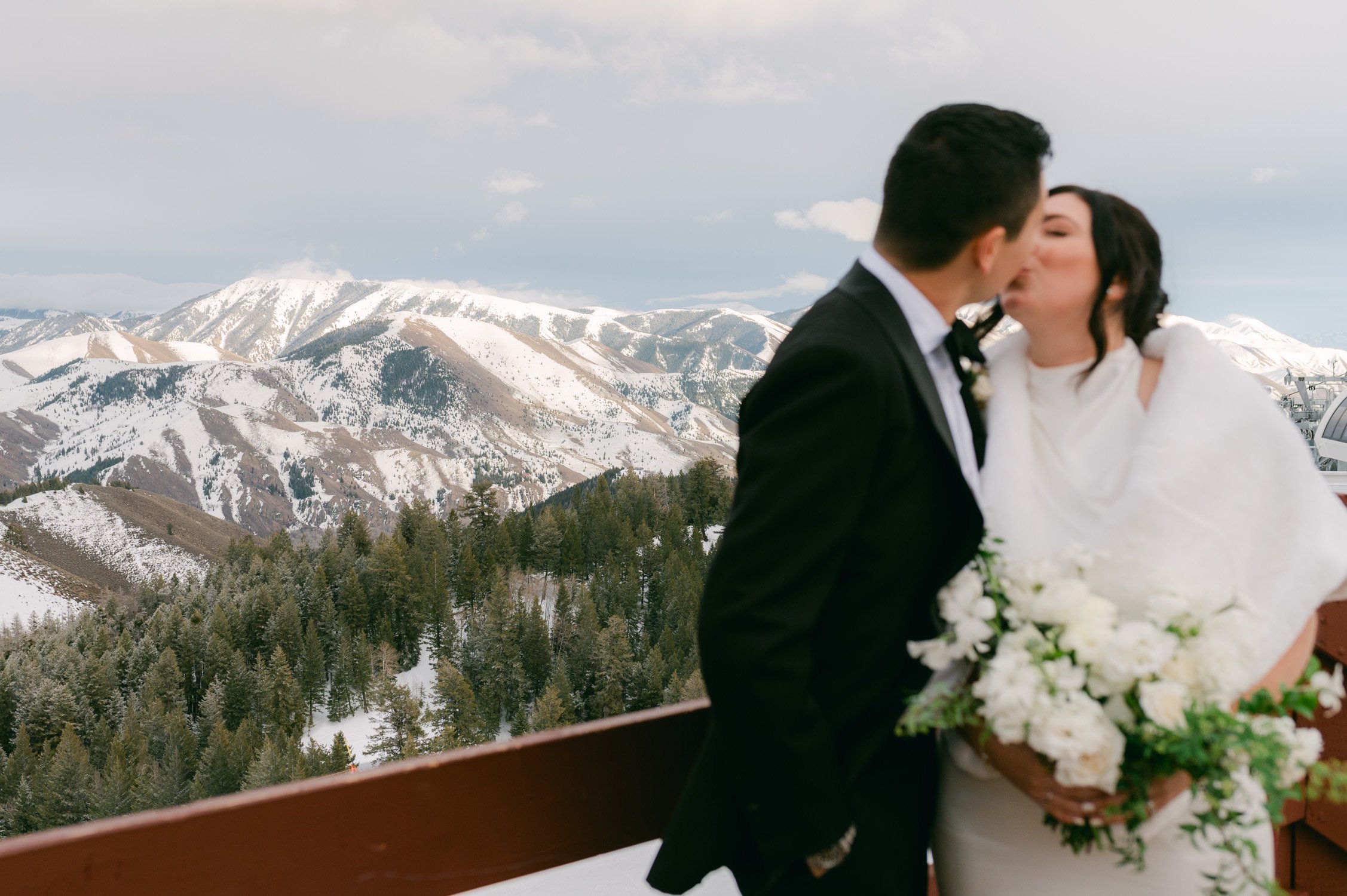 Sun Valley Roundhouse Wedding photo of the newlywed couple kissing with mountains in the background