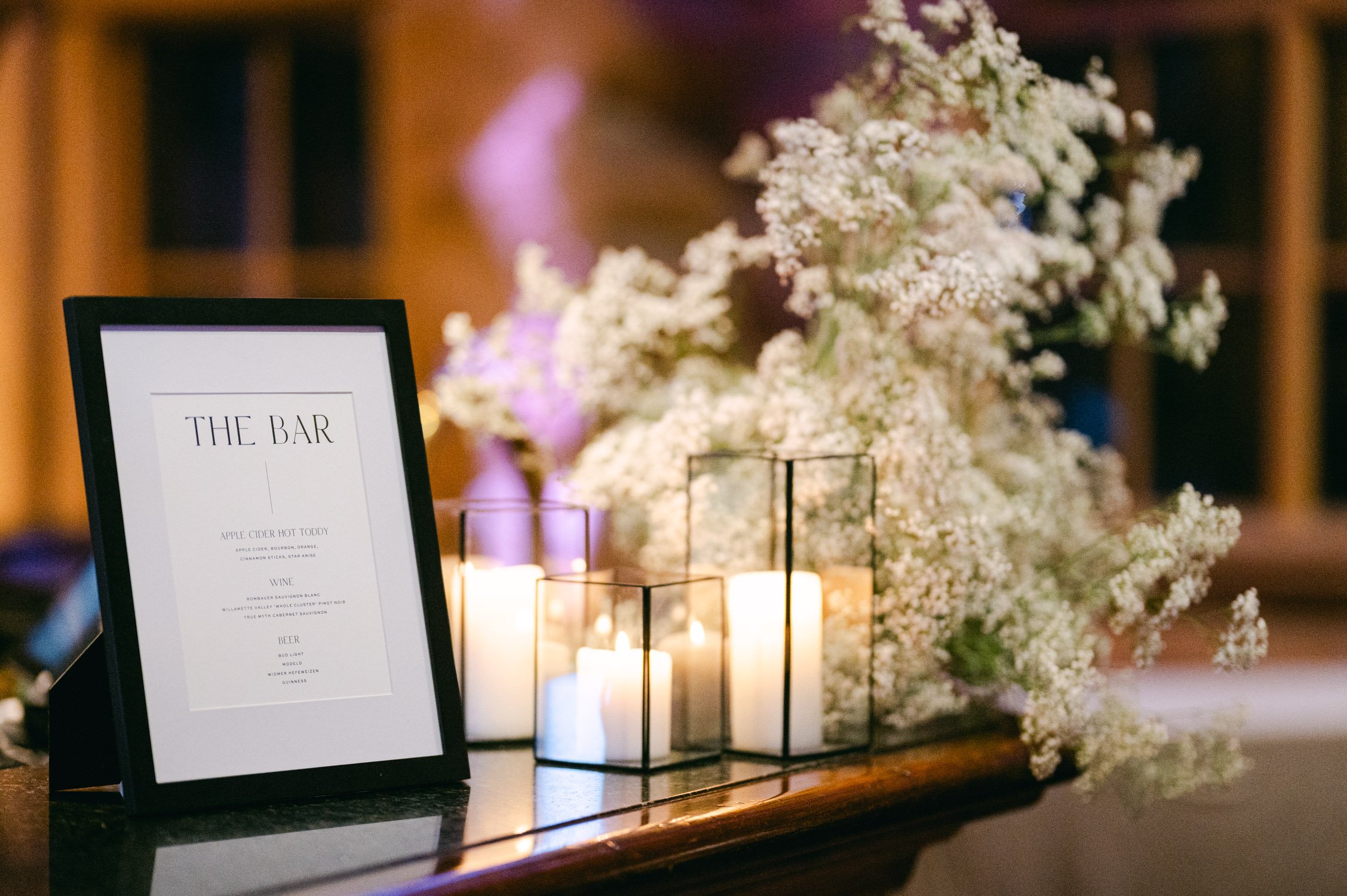 Sun Valley Roundhouse Wedding photo of the bar menu in minimal design, candles, and white flower setup for the reception