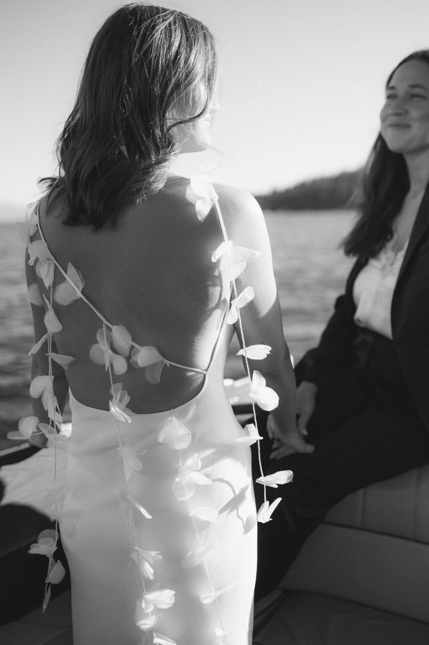 A Lake Tahoe summer wedding welcome party at garwoods, photo of the bride in a romantic backless wedding dress on a boat in Lake Tahoe