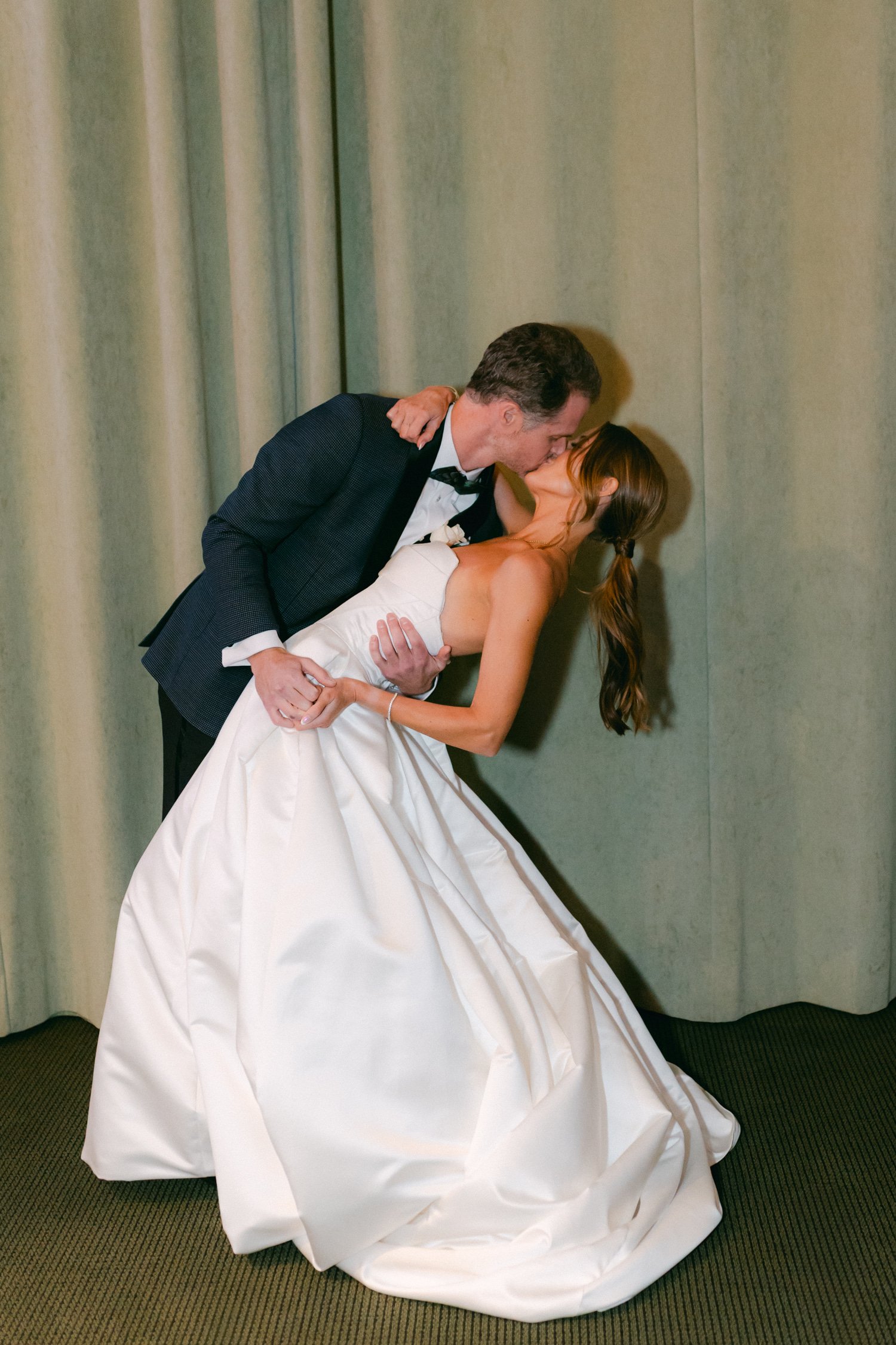 PlumpJack Wedding, photo of the bride and groom sharing a kiss with a curtain backdrop