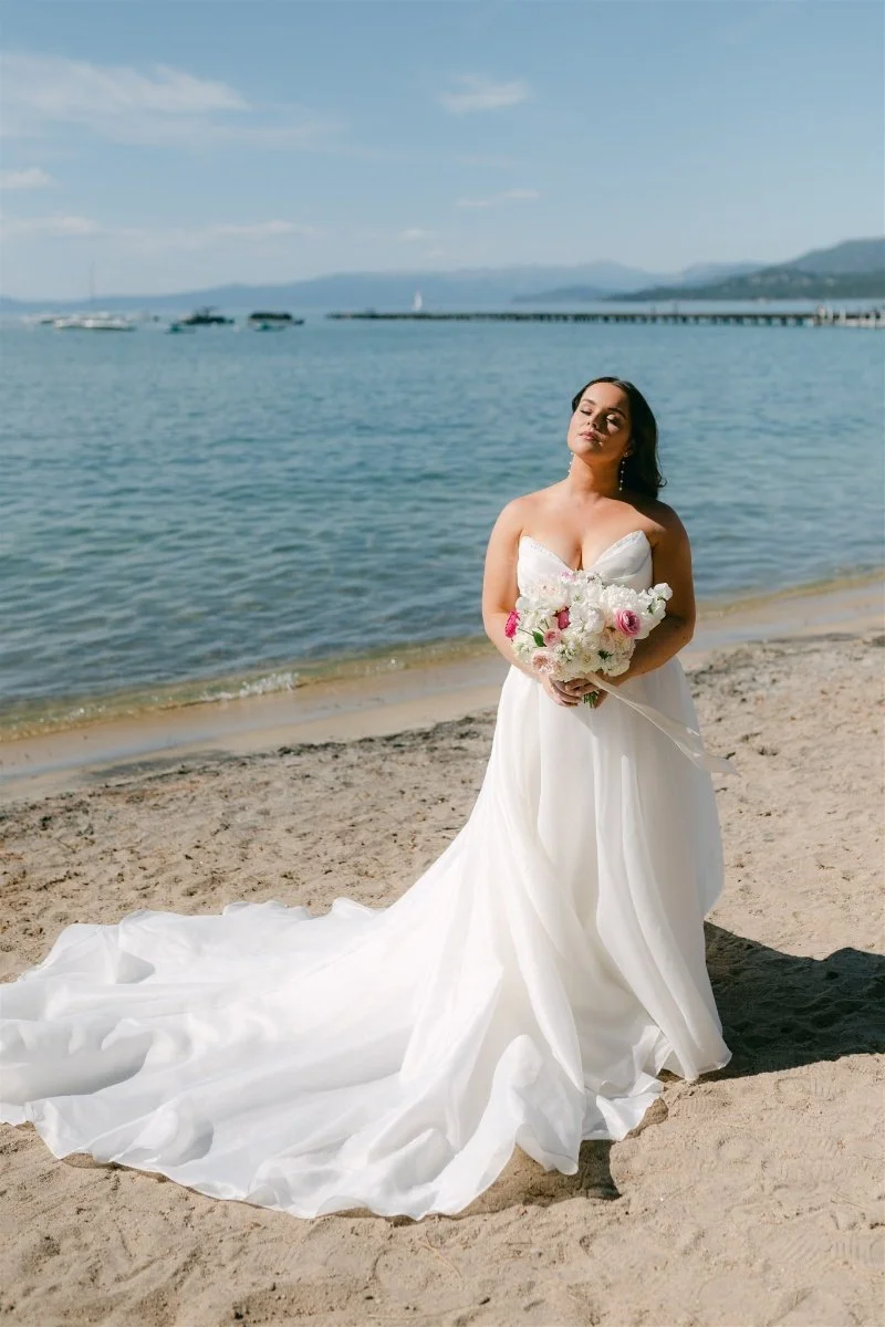 Beach Retreat &amp; Lodge at Tahoe wedding, photo of the bride in a strapless wedding gown with a flowing train on the sandy shoreline
