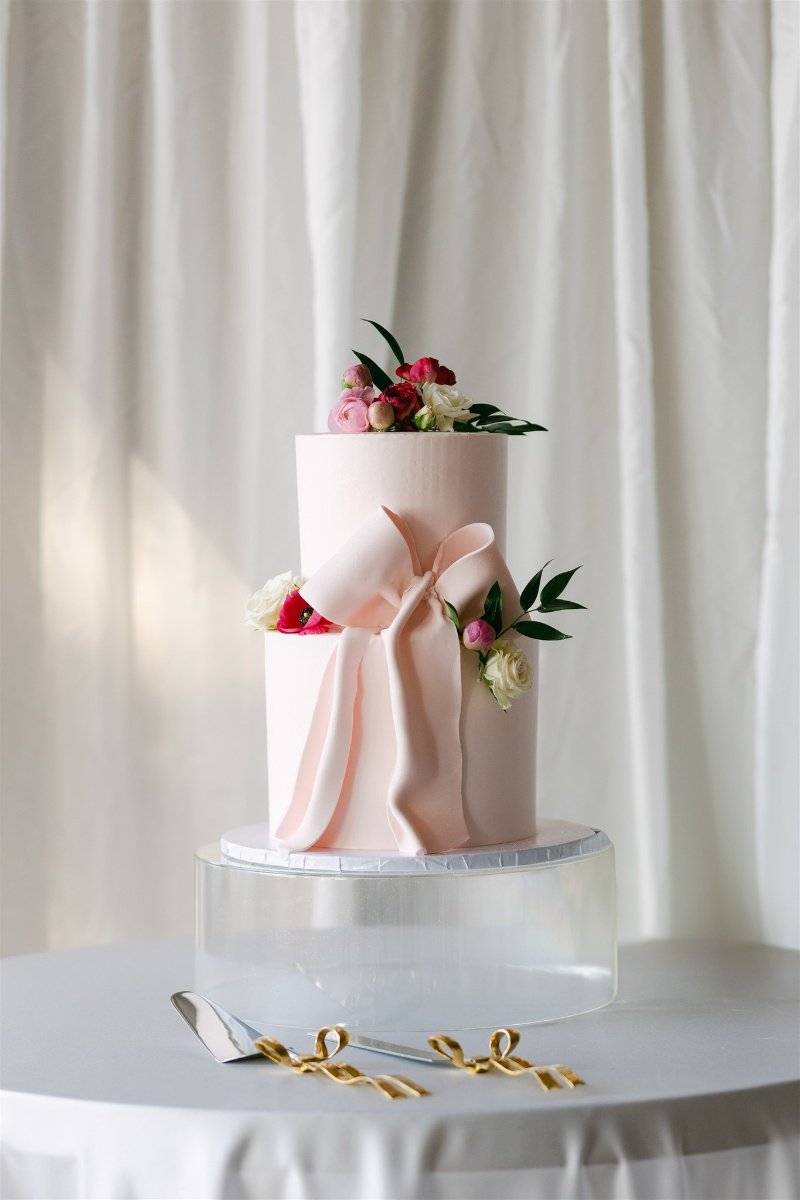 Beach Retreat &amp; Lodge at Tahoe wedding, photo of a pink wedding cake adorned with oversized bow details and fresh florals