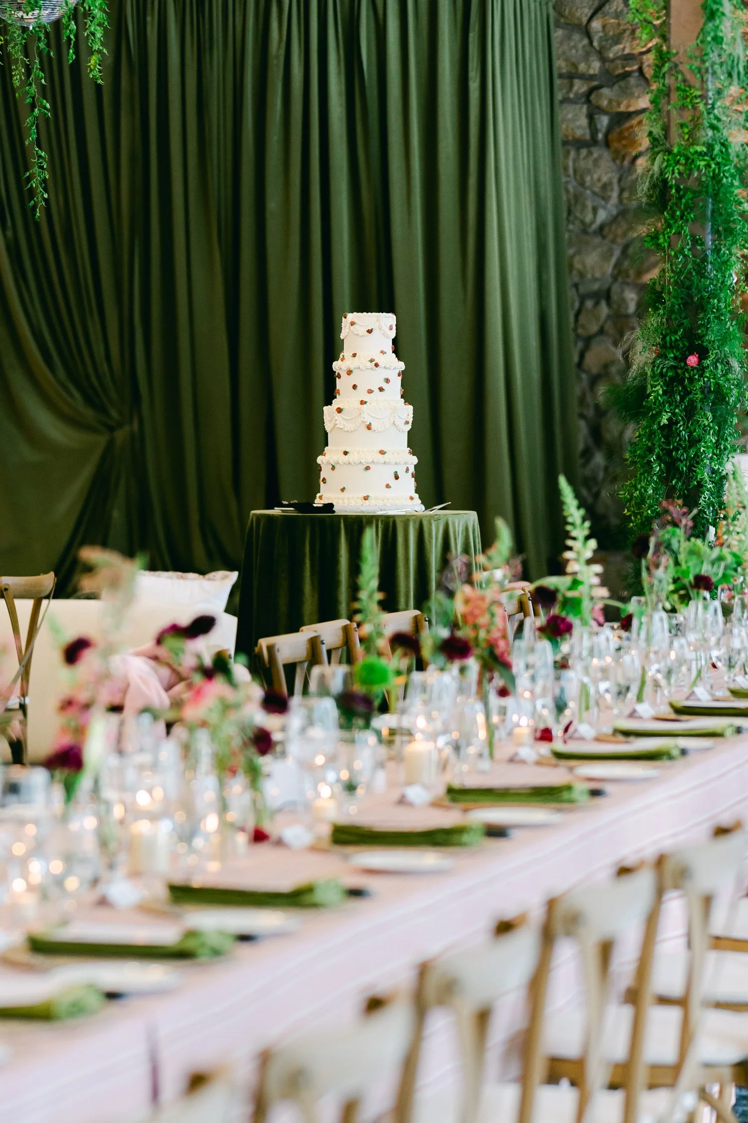 Palisades wedding venue, photo of a beautifully decorated wedding reception venue, featuring a central tiered wedding cake positioned on a green-draped table. 