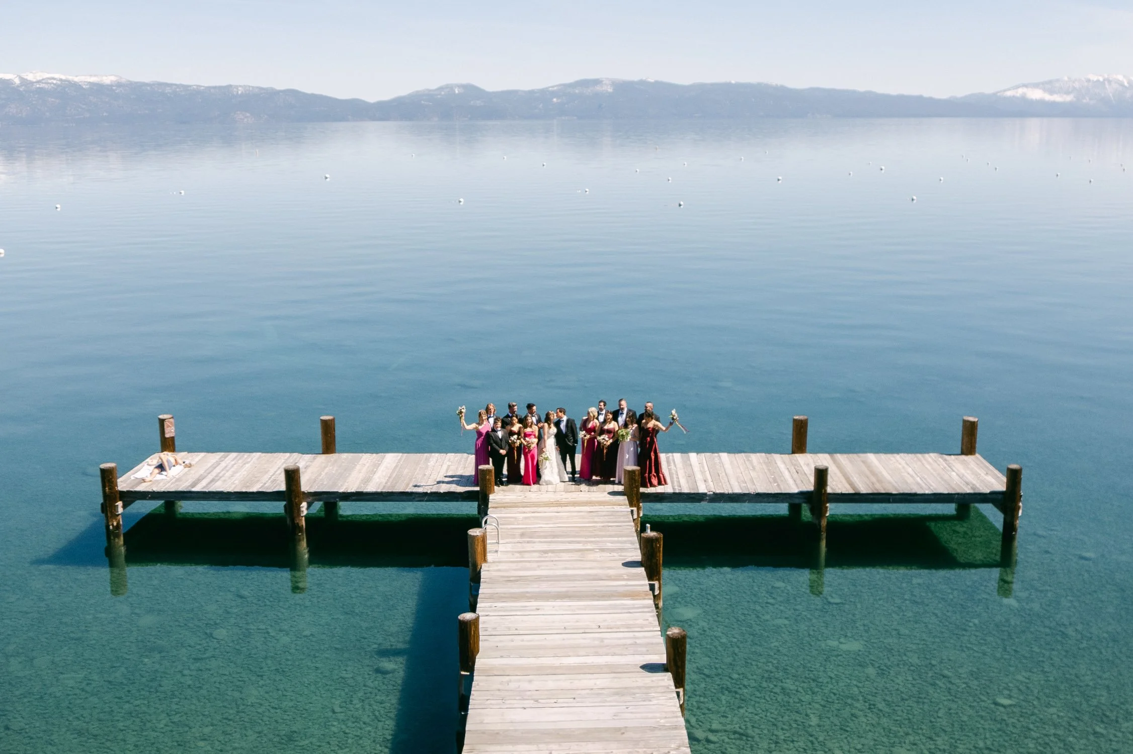 Palisades wedding venue, drone photo of wedding party posing for a photograph on a wooden dock over calm water