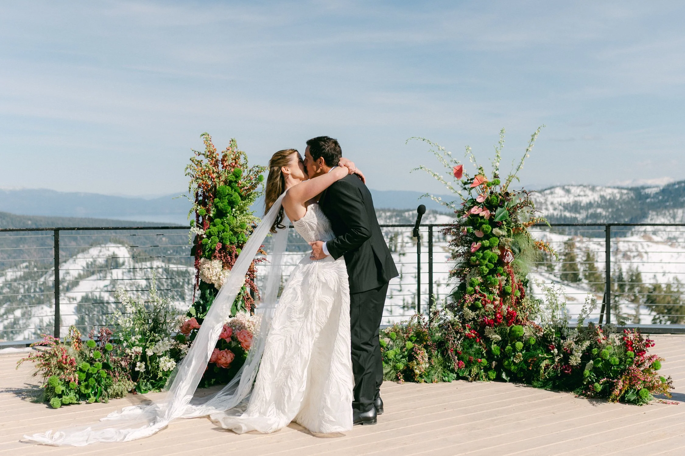 High Camp Ceremony, photo of the couple kissing during an outdoor wedding ceremony featuring a stunning panoramic view of the snow-capped Sierra Nevada mountains. 