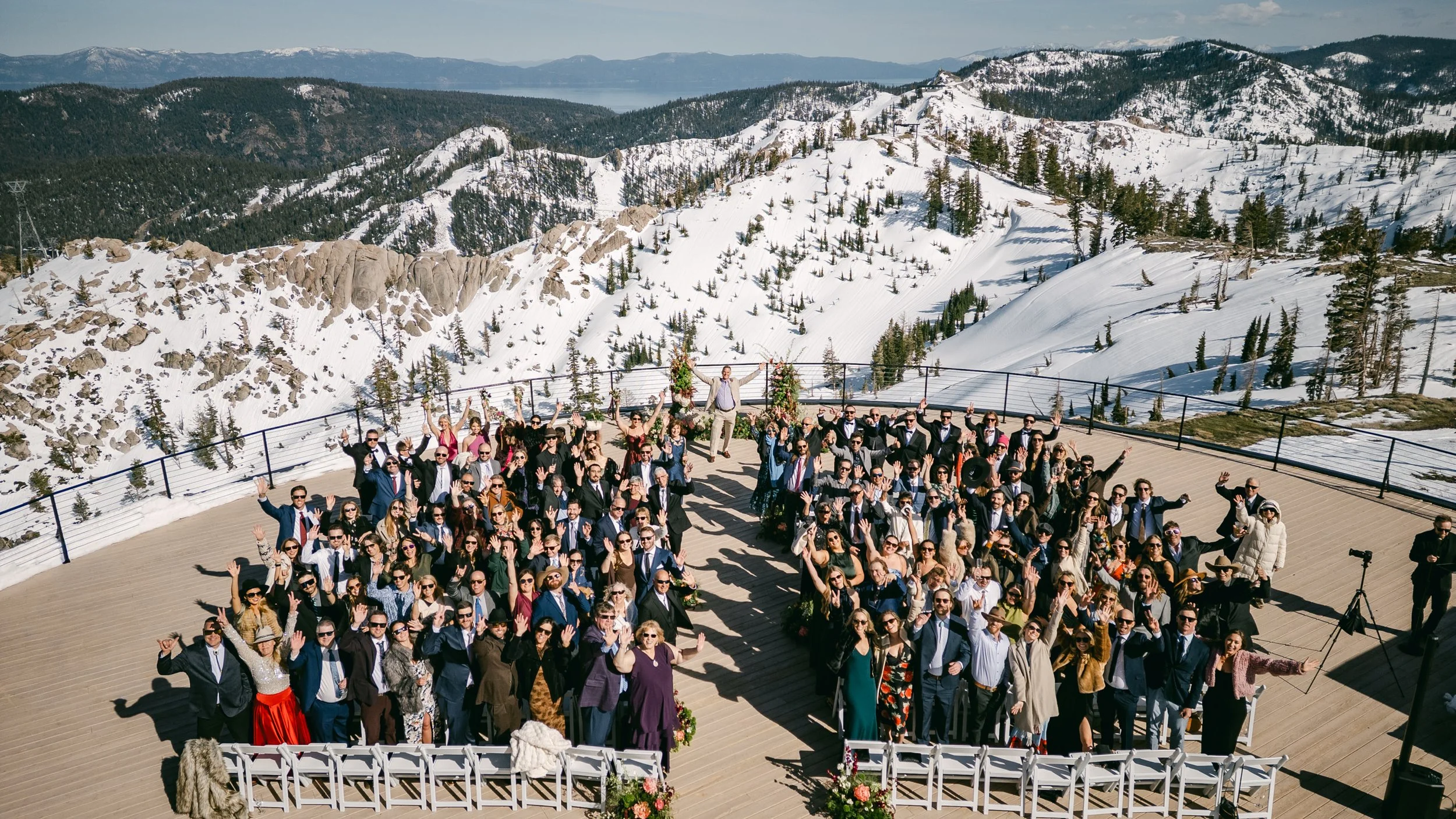 High Camp Ceremony, photo of an outdoor wedding ceremony taking place on a sun-drenched deck at Palisades Tahoe ski resort, surrounded by snow-capped mountains. 
