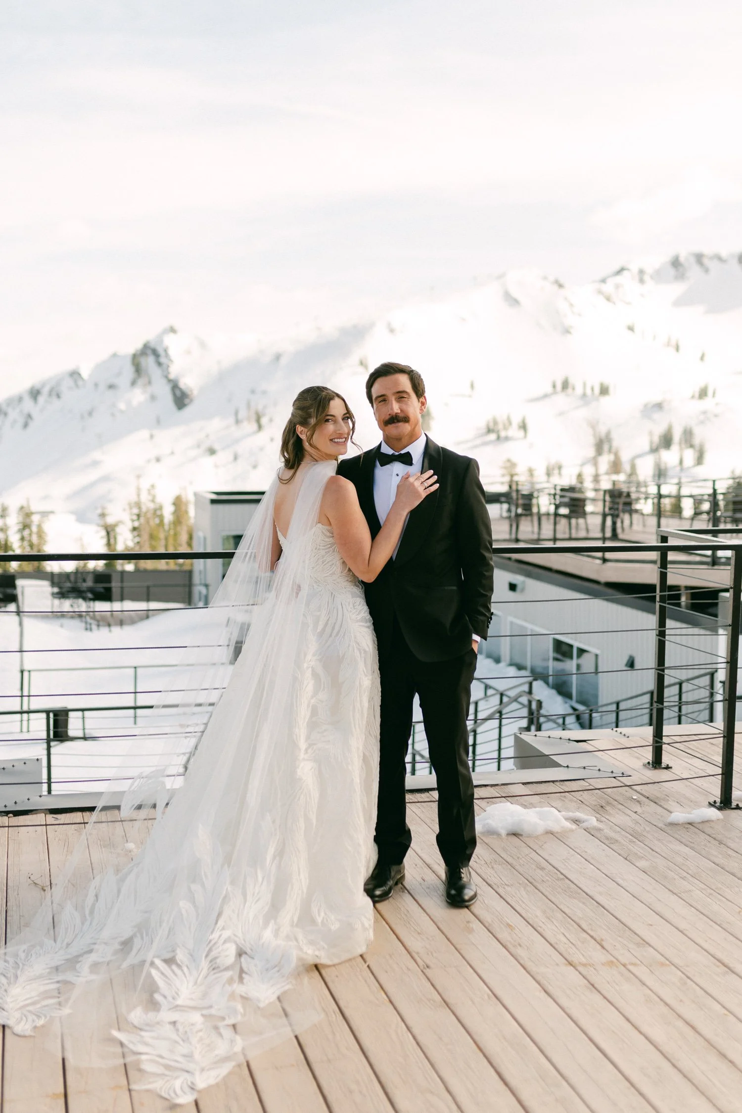 Palisades wedding venue, photo of the newlyweds on their wedding day in a snowy mountain setting with the bride in a detailed white gown and veil, and the groom in a classic black tuxedo.