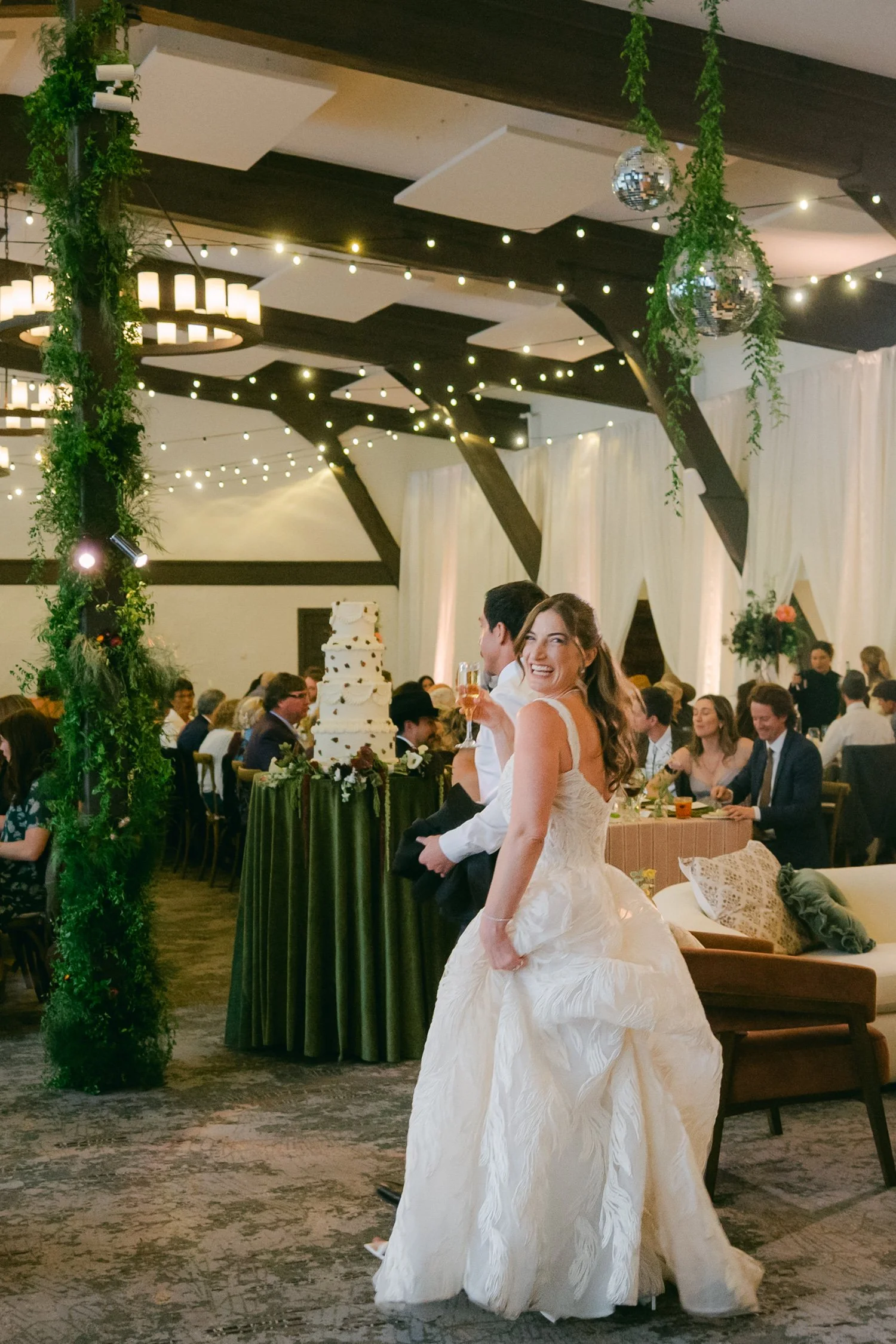 Palisades wedding venue, photo of a candid moment of a bride walking through her wedding reception, holding a glass of champagne