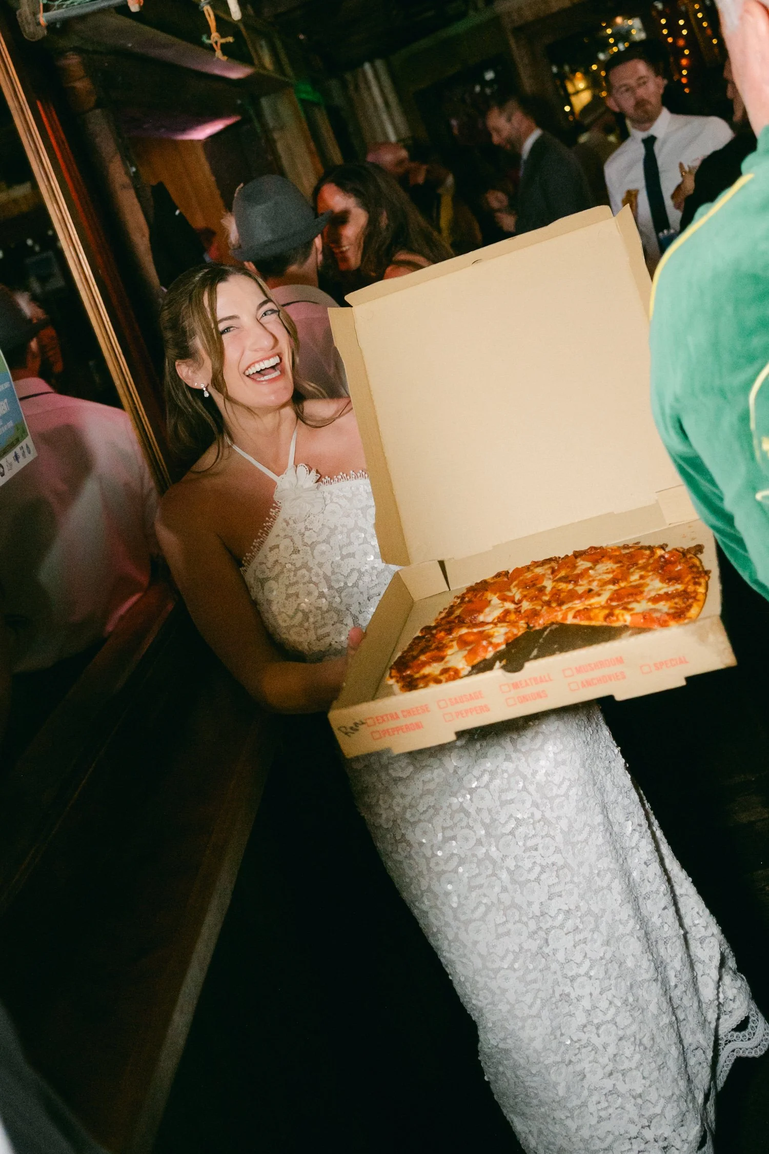 Palisades wedding venue, photo of a joyful moment with the bride enjoying a late-night pizza snack for the afterparty festivities 