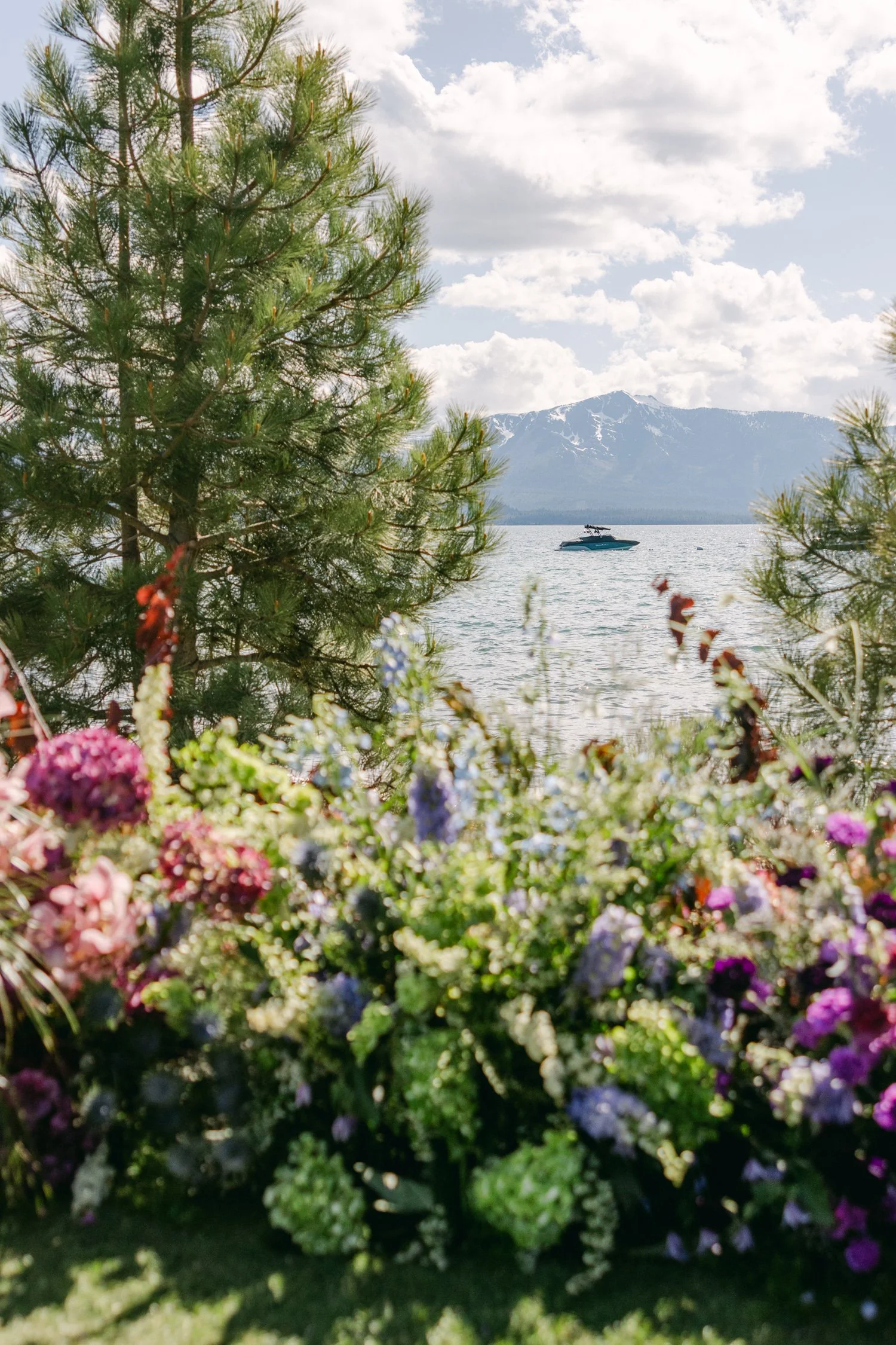 Edgewood maximalist wedding, photo of lakeside wedding ceremony featuring vibrant pink, purple, and green floral arrangements framing a view of Lake Tahoe