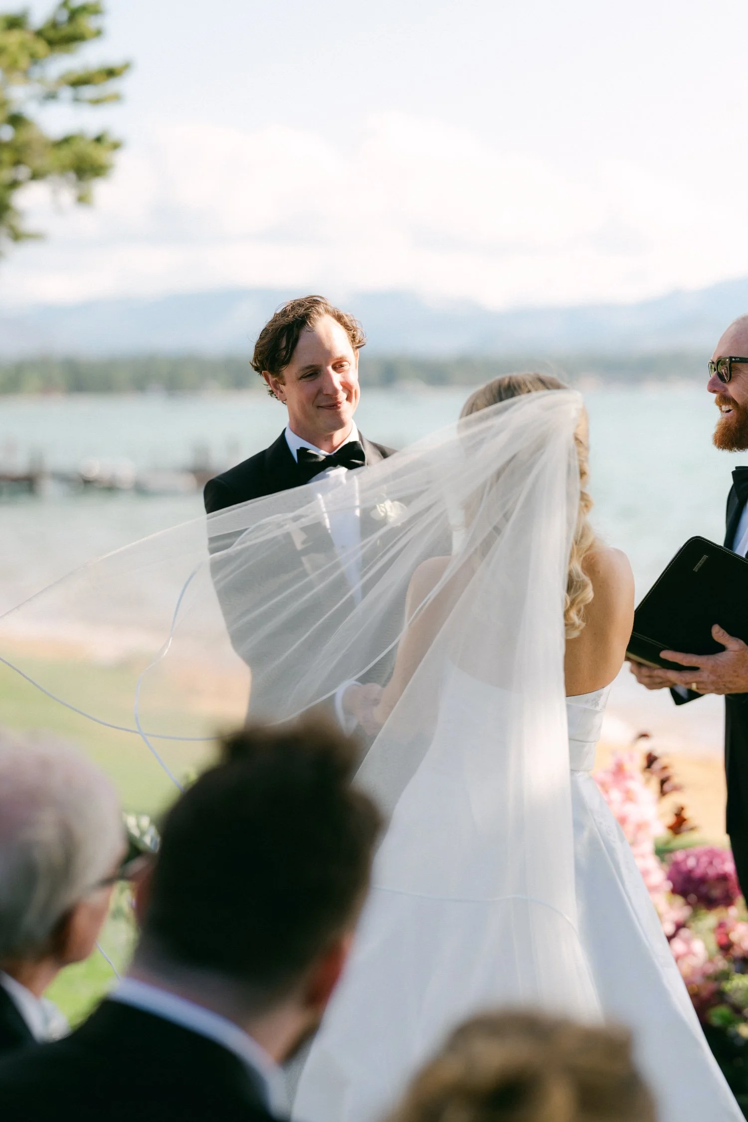 Edgewood maximalist wedding, photo of the bride and groom during a lakeside wedding ceremony with mountains in the background.