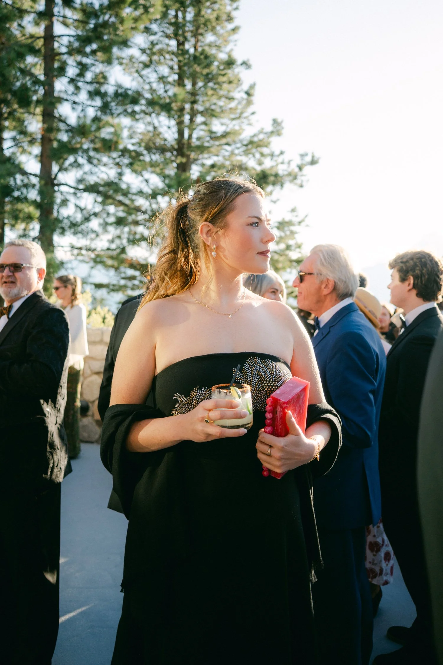 Edgewood maximalist wedding, photo of stylish wedding guest wearing a black strapless gown featuring delicate crystal floral embellishments during an outdoor reception
