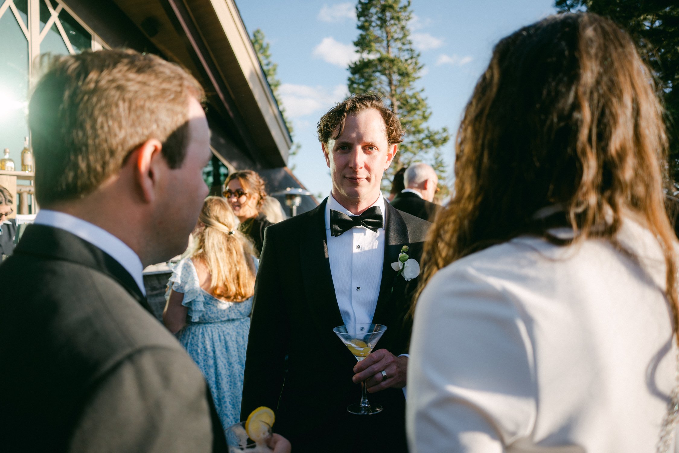 Edgewood maximalist wedding, photo of the groom wearing a classic black tuxedo mingling with guests during the afternoon reception