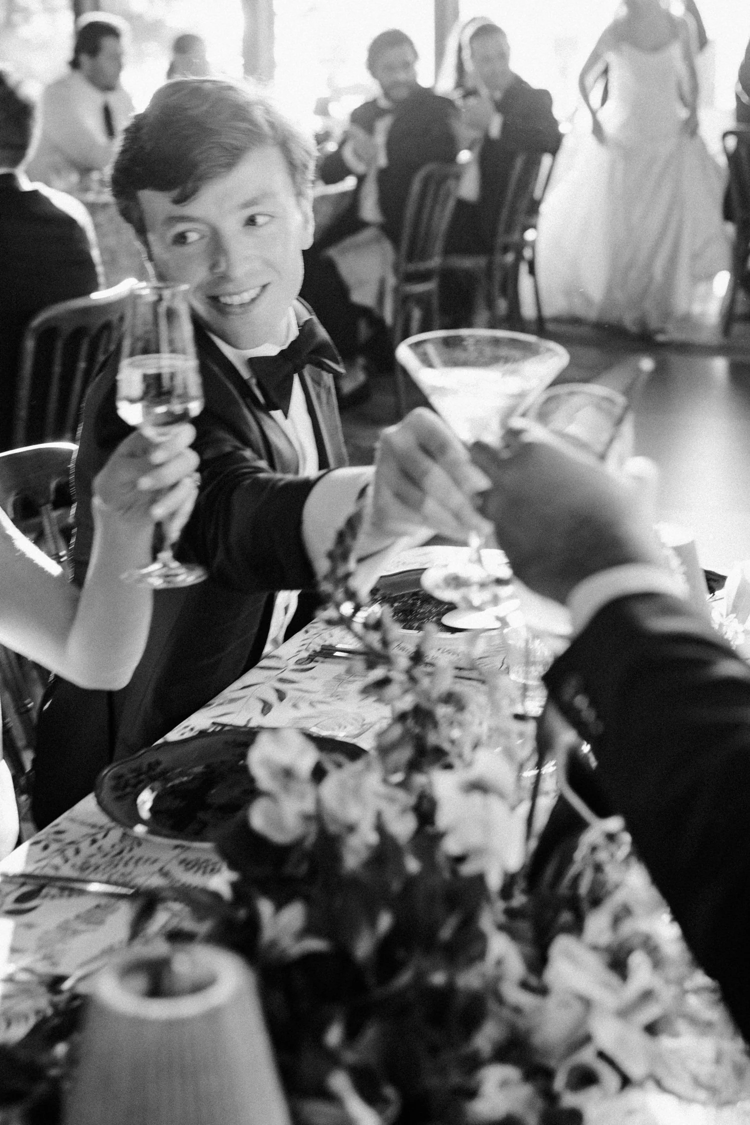 Edgewood maximalist wedding, photo of a candid black and white moment featuring guests holding up champagne glasses at a wedding reception