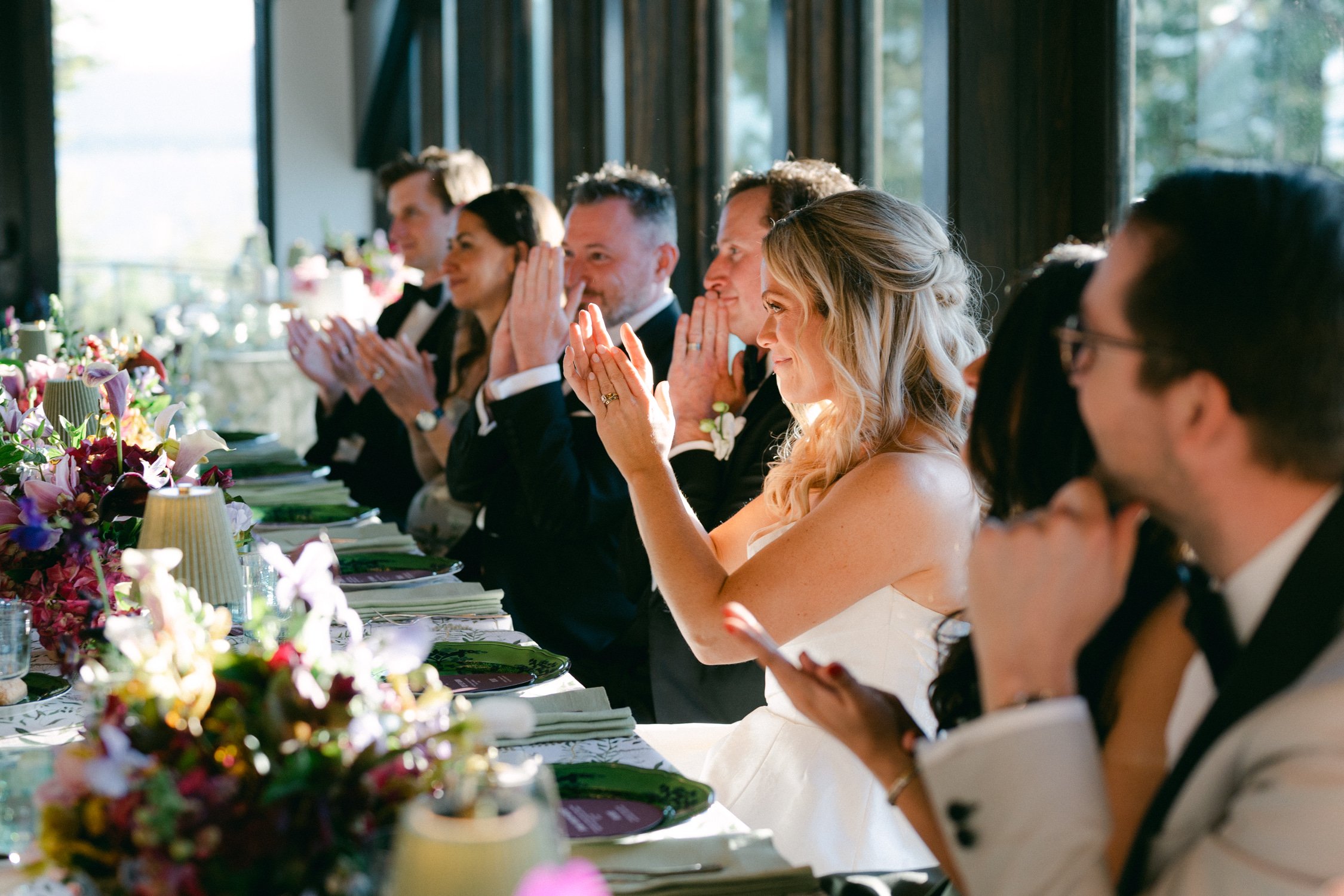 Edgewood maximalist wedding, photo of guests clapping along a long table decorated with floral arrangements