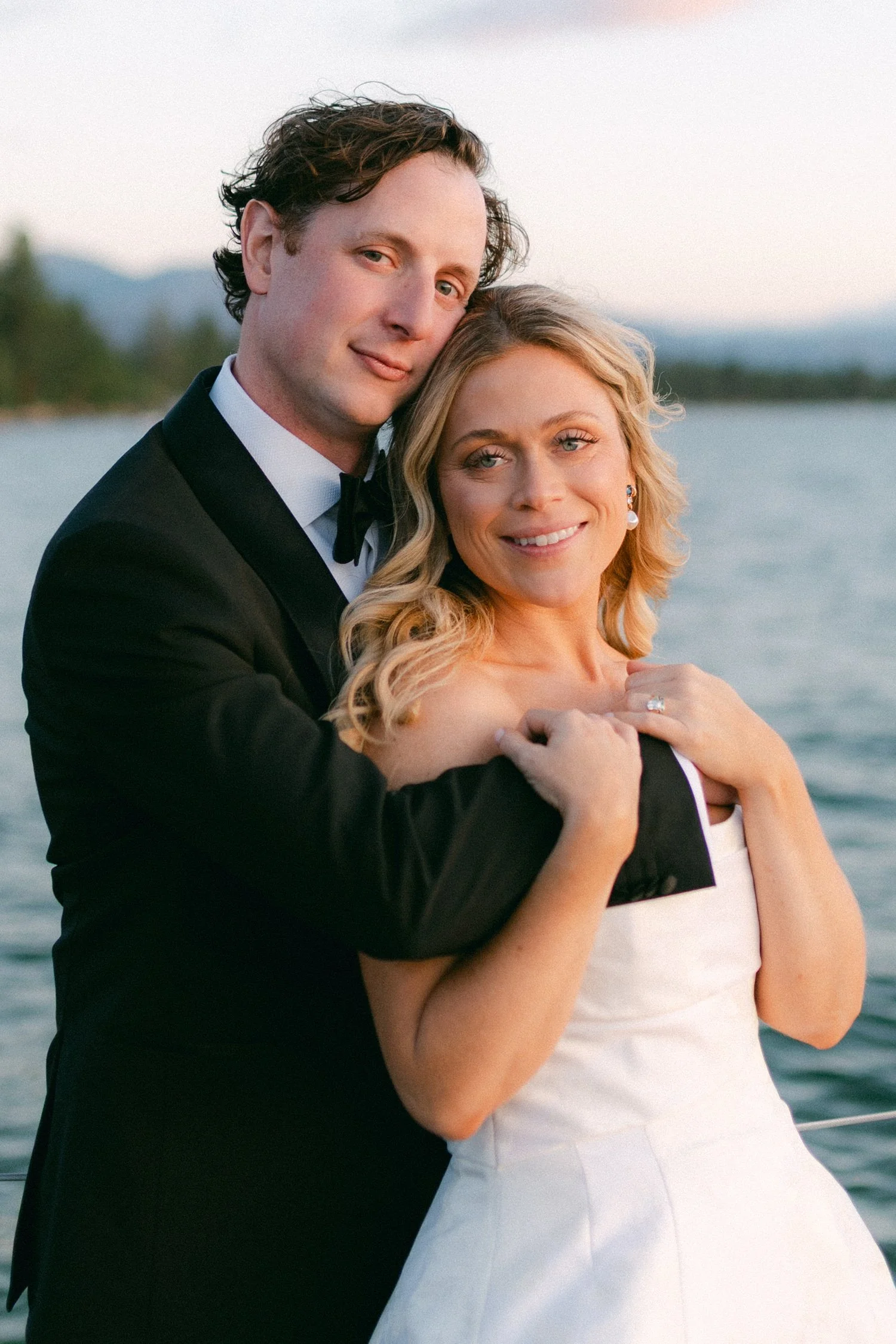 Edgewood maximalist wedding, photo of the newlyweds captured in a classic, romantic embrace by the lake during sunset
