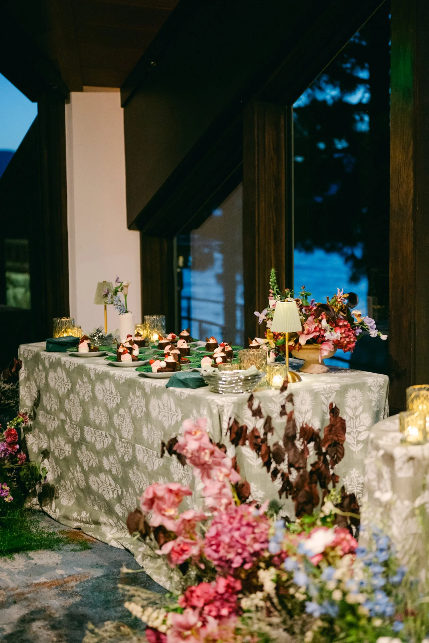 Edgewood maximalist wedding, photo of the dessert table setup decorated with table lamps and lush floral arrangements