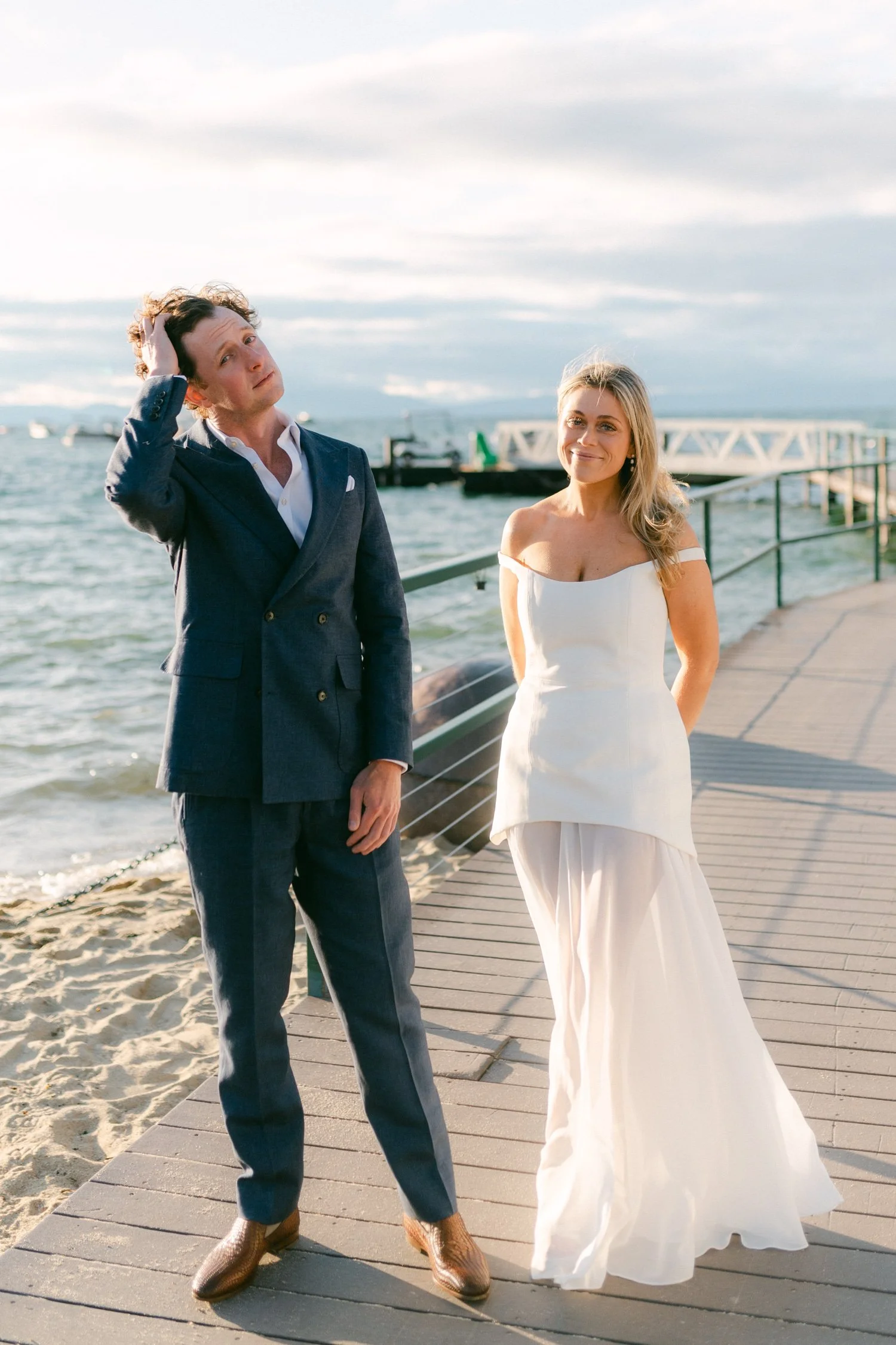 Riva Grill welcome party, photo of the couple posing together by the water, featuring a strapless dress with a fitted bodice and a sheer, flowing skirt overlay