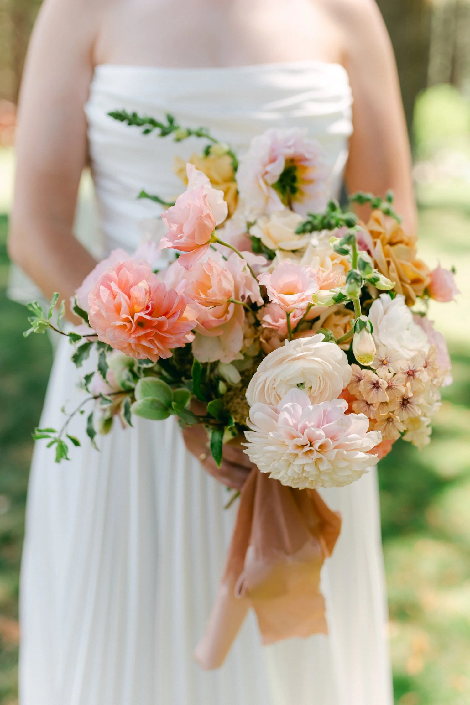 Lake Tahoe 4-H Camp wedding photos, photo of bridal bouquet featuring spring florals including roses and dahlias in peach, pink, and cream hues