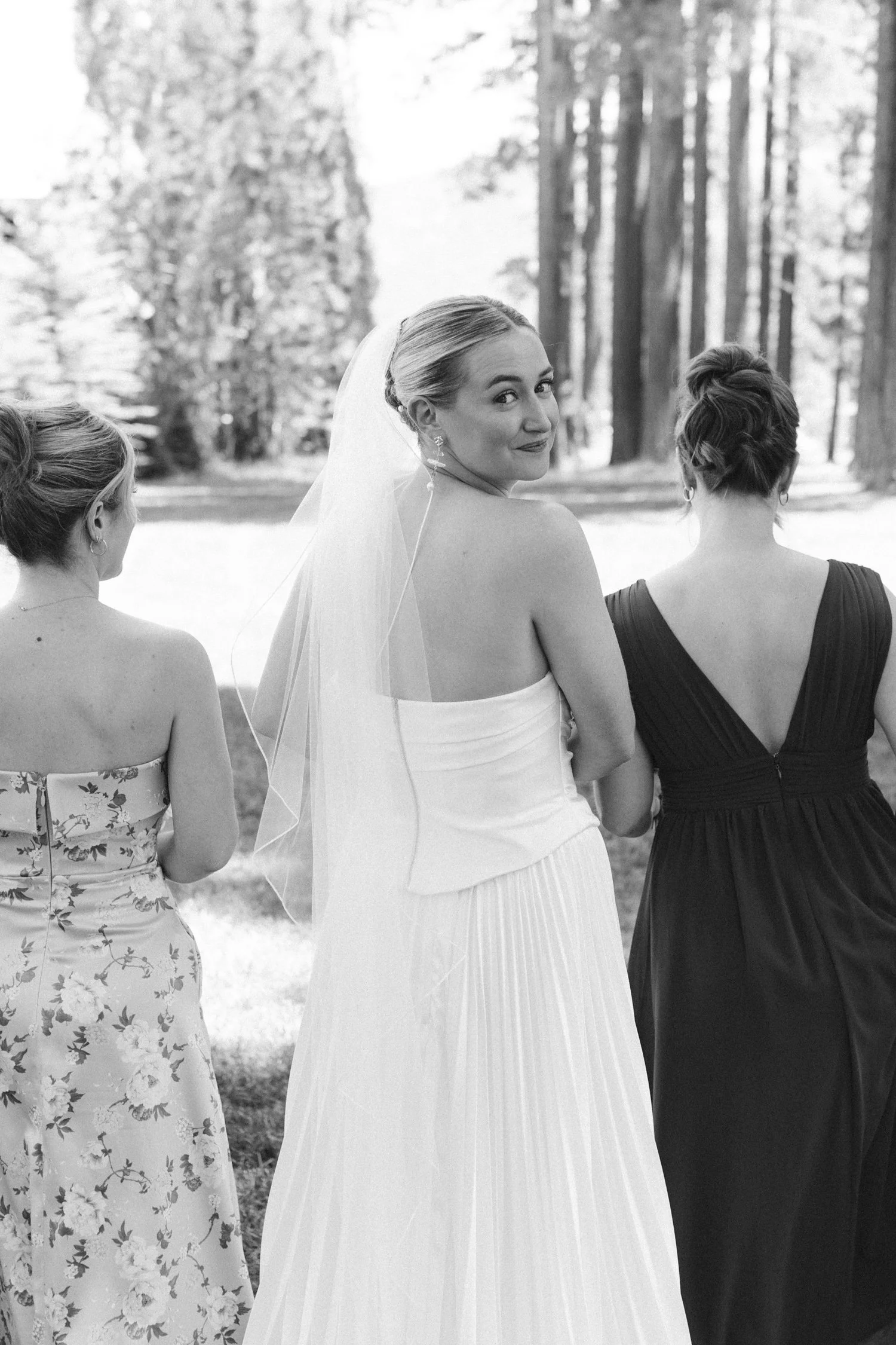 Lake Tahoe 4-H Camp wedding photos, photo of the bride in a white, pleated gown and veil walking alongside her bridesmaids.