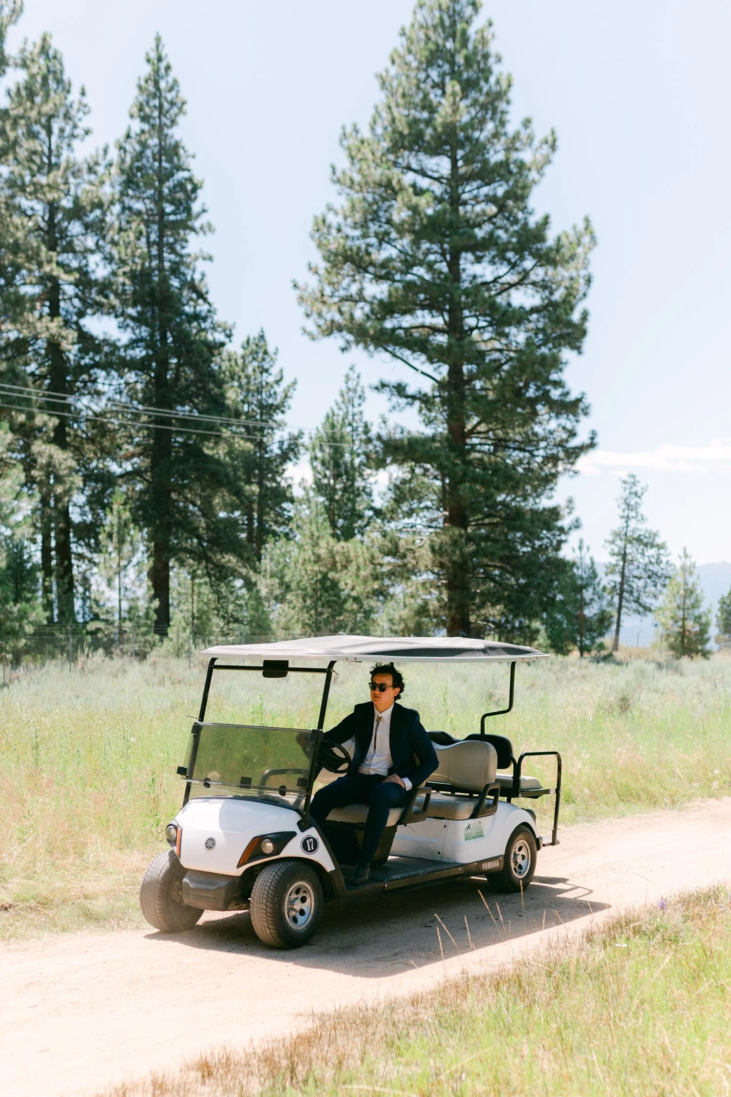 Lake Tahoe 4-H Camp wedding photos, photo of the wedding guest driving a golf cart on a dirt path in a wooded area