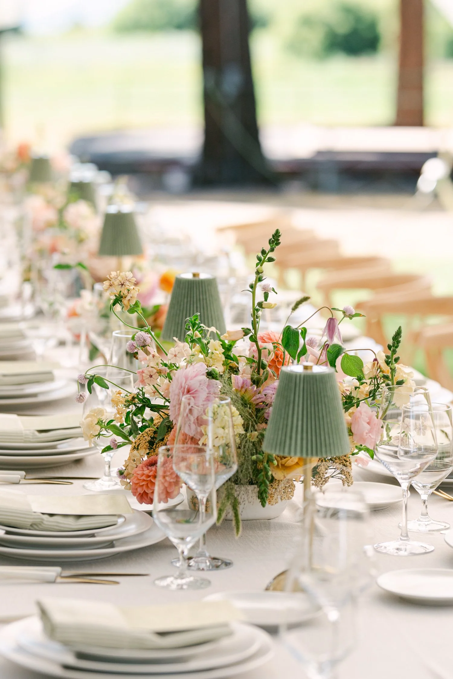 Lake Tahoe 4-H Camp wedding photos, photo of wedding reception tablescape features long dining tables decorated with colorful pastel floral arrangements and green pleated lamp-style table lights