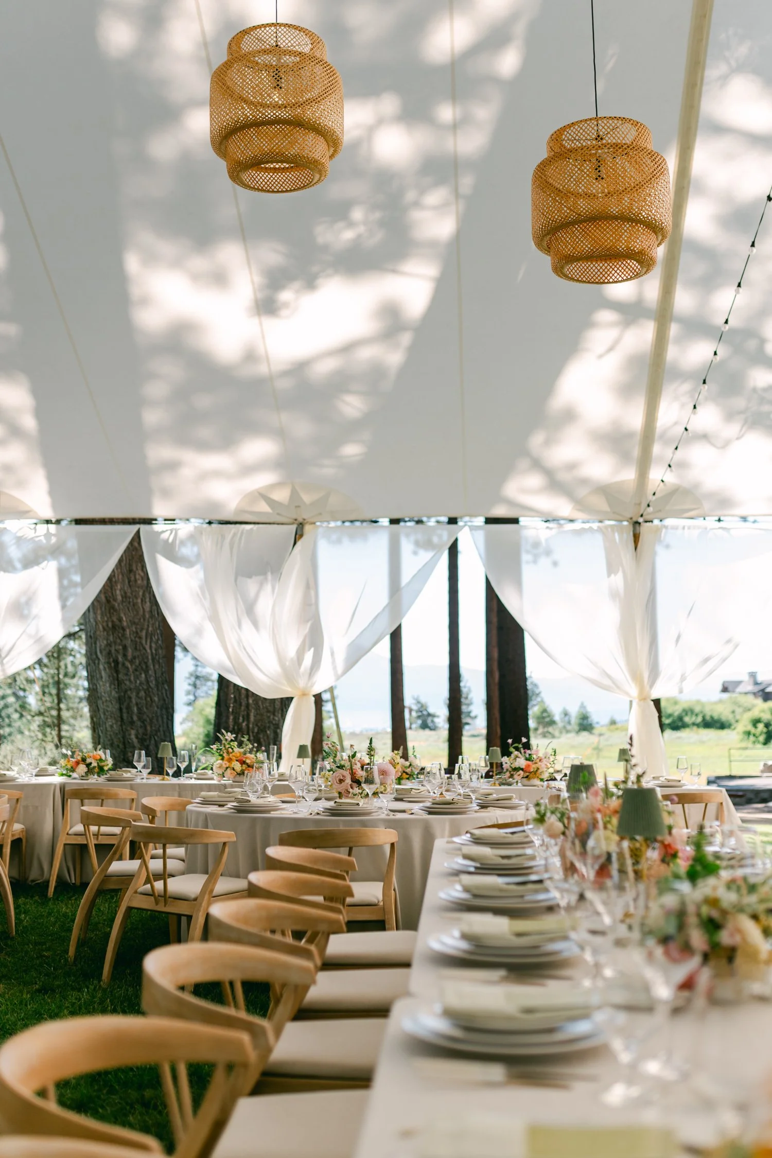Lake Tahoe 4-H Camp wedding photos, photo of ustic-chic wedding reception featuring woven rattan pendant lights and elegant white fabric drapery hanging in a large tent.