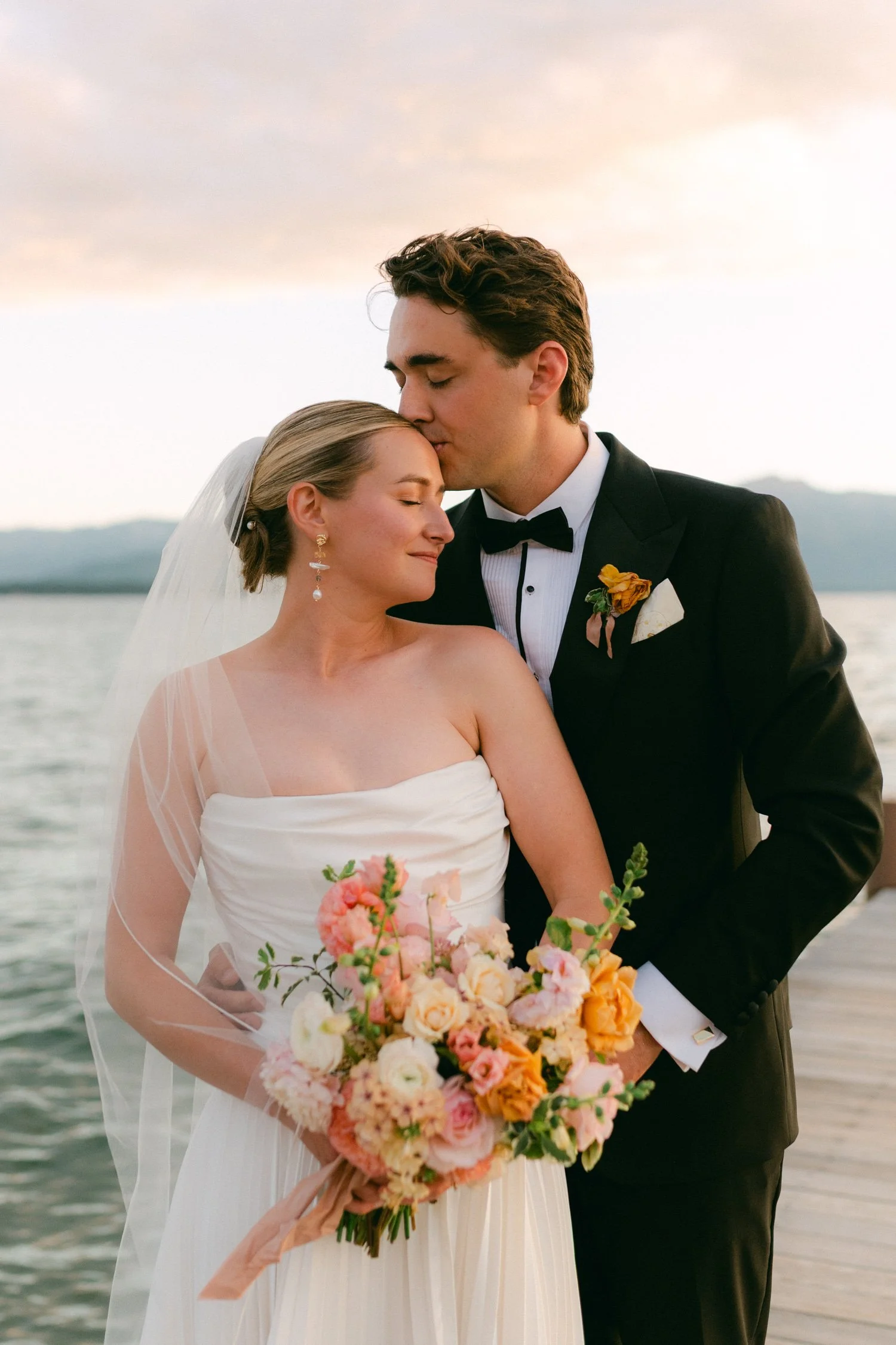 Lake Tahoe 4-H Camp wedding photos, photo of the newlywed couple embracing on a dock overlooking a lake at sunset
