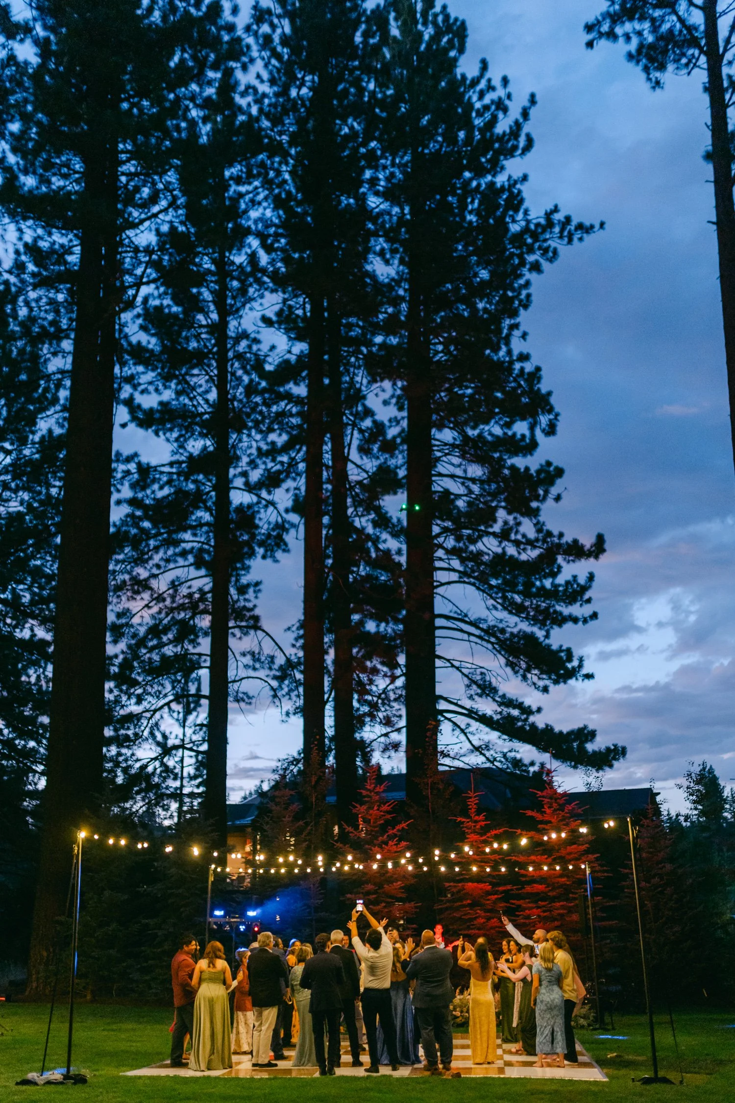 Lake Tahoe 4-H Camp wedding photos, photo of the evening wedding reception featuring a dance floor set up beneath tall pine trees.