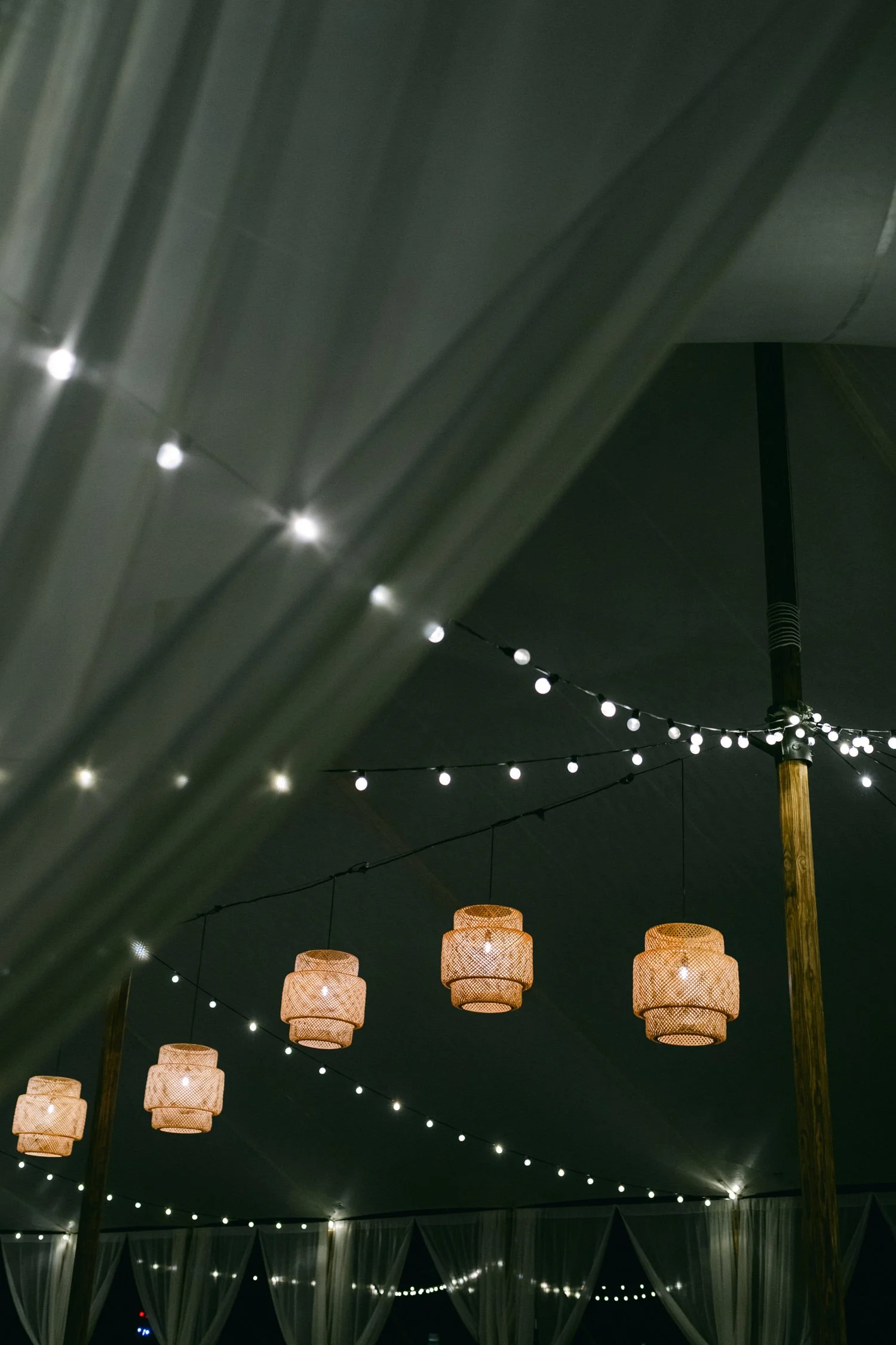 Lake Tahoe 4-H Camp wedding photos, photo of a tent setup featuring warm-toned woven rattan pendant lampshades for a rustic, bohemian ambiance