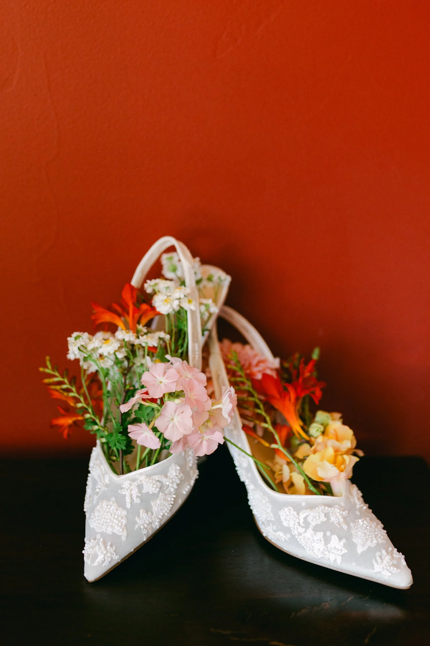 Zephyr Lodge wedding, photo of white embroidered wedding heels featuring delicate floral applique and are filled with a colorful floral arrangement
