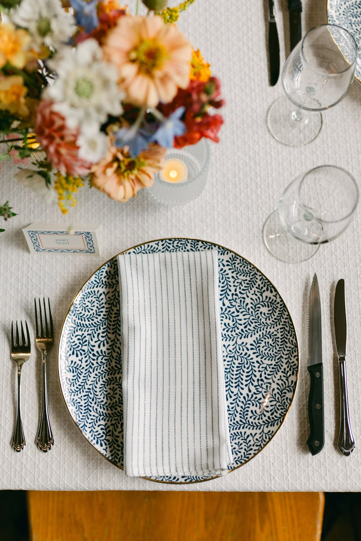 Zephyr Lodge wedding, photo of table reception setup with a patterned blue and white porcelain plate styled with striped linens and colorful garden florals.