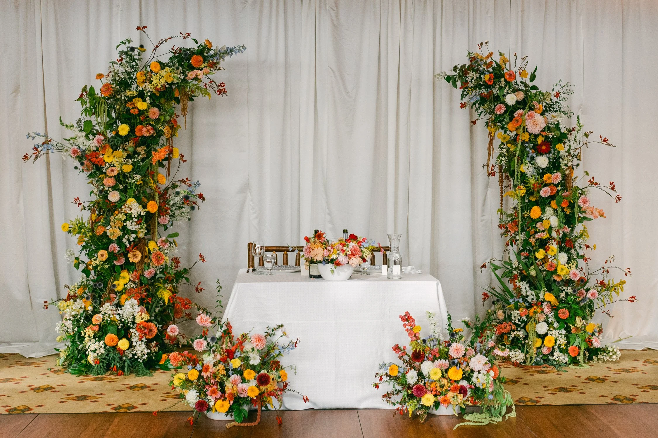 Zephyr Lodge wedding, photo of the wedding sweetheart table featuring vibrant floral arches and colorful flower installations