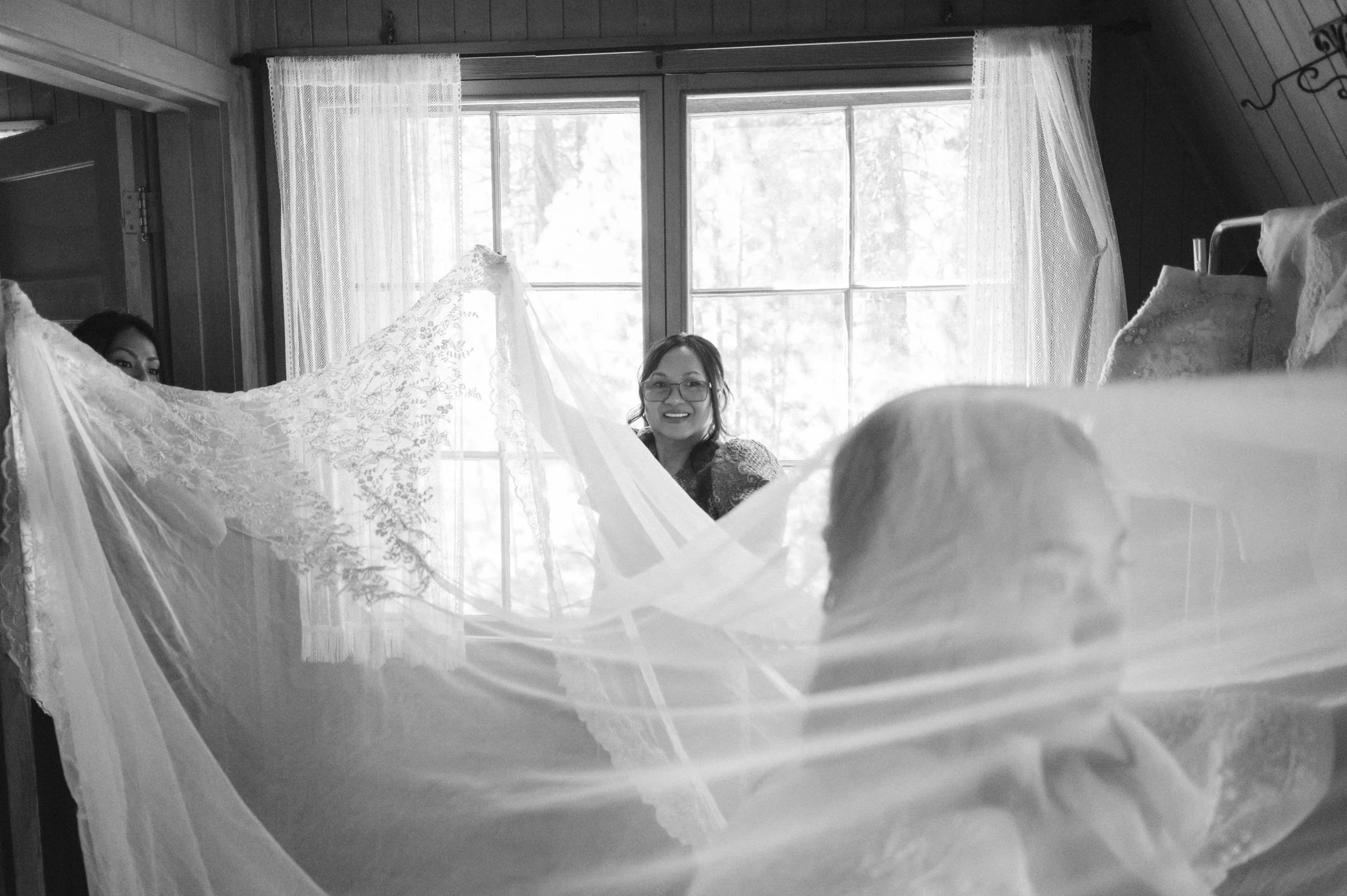 A Valhalla Lake Tahoe Wedding, photo of a black-and-white candid photo of a bride getting ready framed by a delicate lace veil and window light.